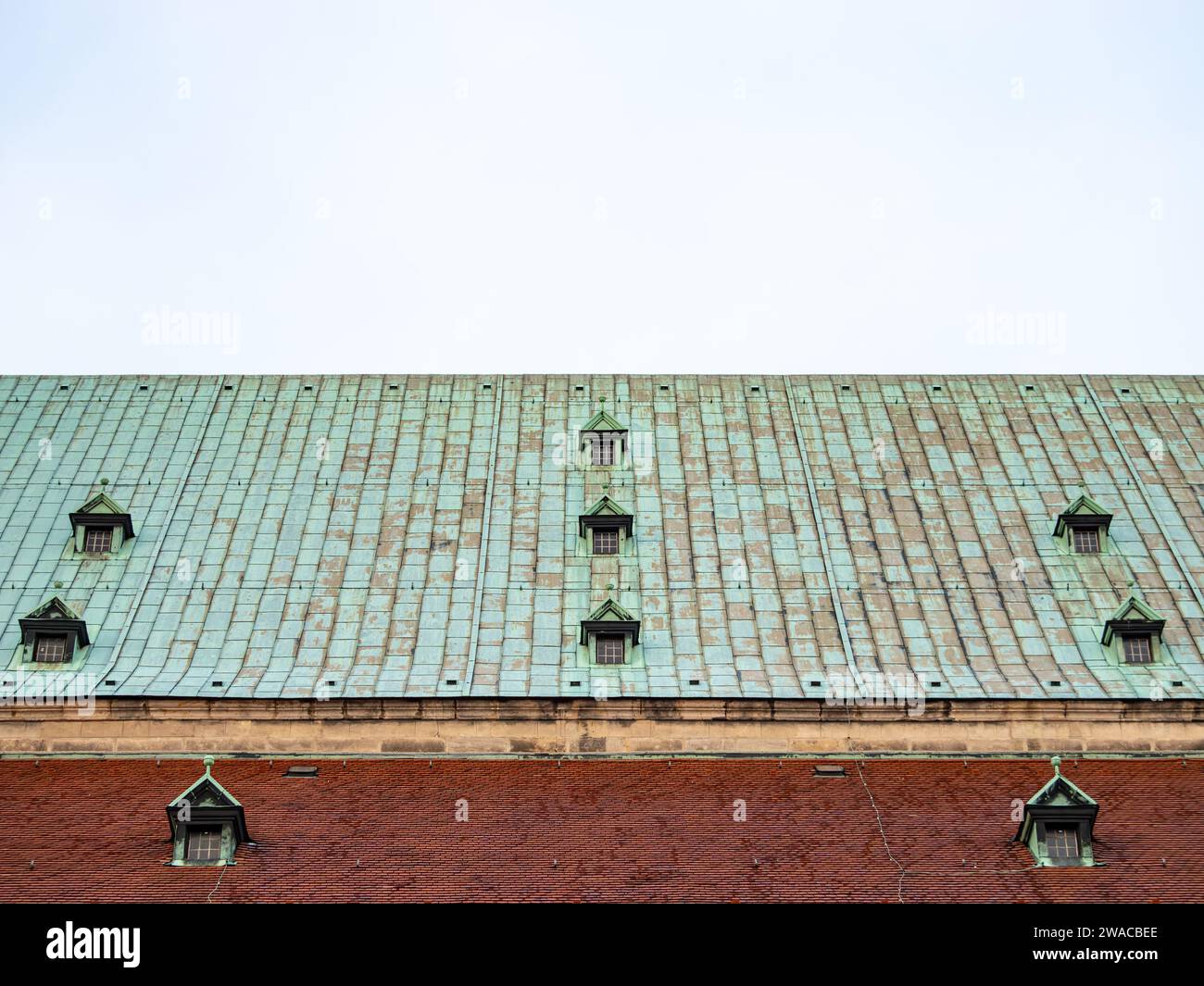 Alte Dachterrasse mit verwitterten Kupferblechen und Dachfenstern. Architekturdetail eines historischen Altbaus als abstrakter Hintergrund. Stockfoto