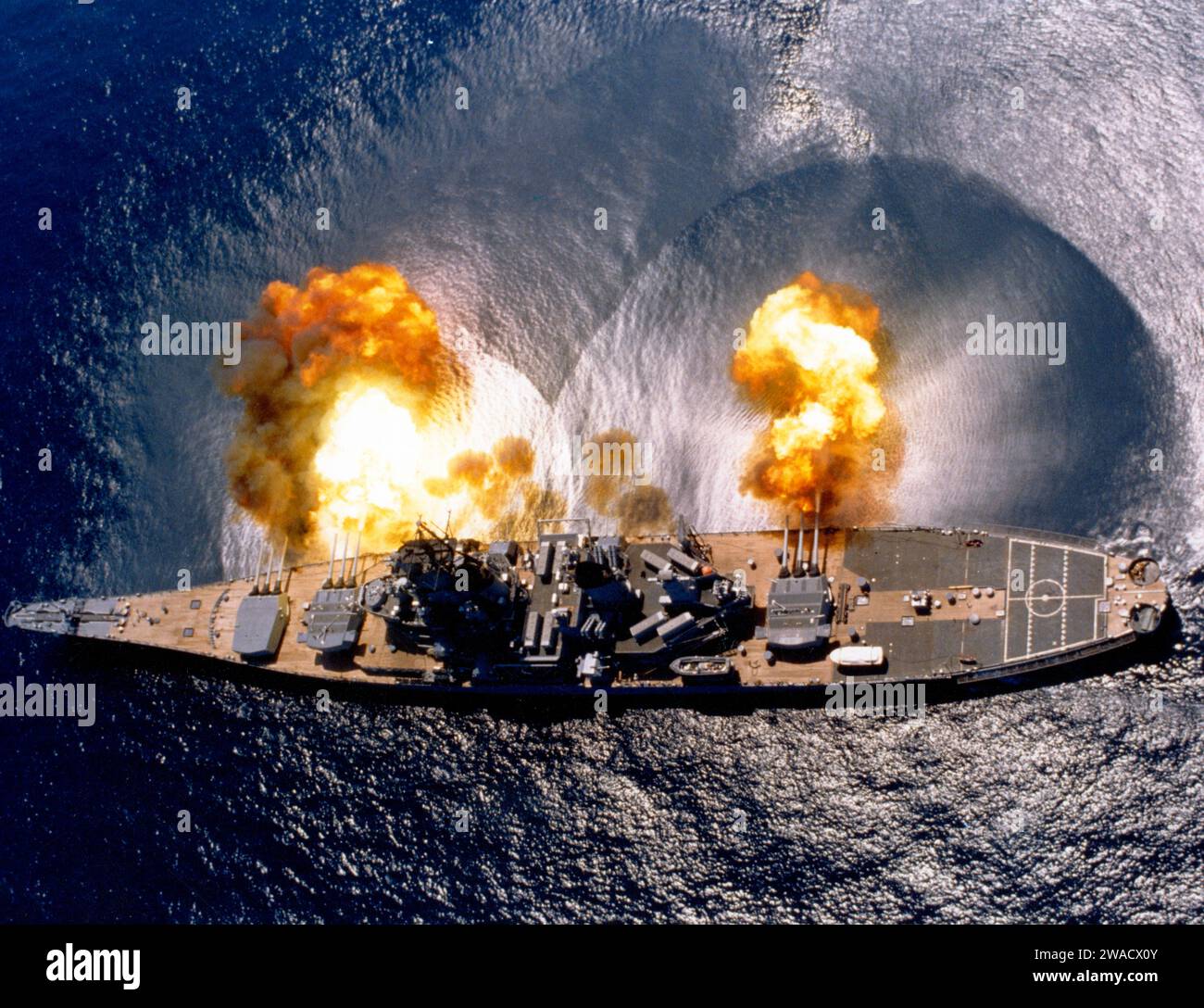 Die USS Iowa (BB-61) feuert während einer Zielübung in der Nähe von Vieques Island, Puerto Rico, eine volle Breite ihrer neun 16″/50 und sechs 5″/38 Geschütze ab. Beachten Sie Gehirnerschütterung auf der Wasseroberfläche und 16-Zoll-Kanonenläufe in unterschiedlichem Rückstoßgrad. 1984 Stockfoto