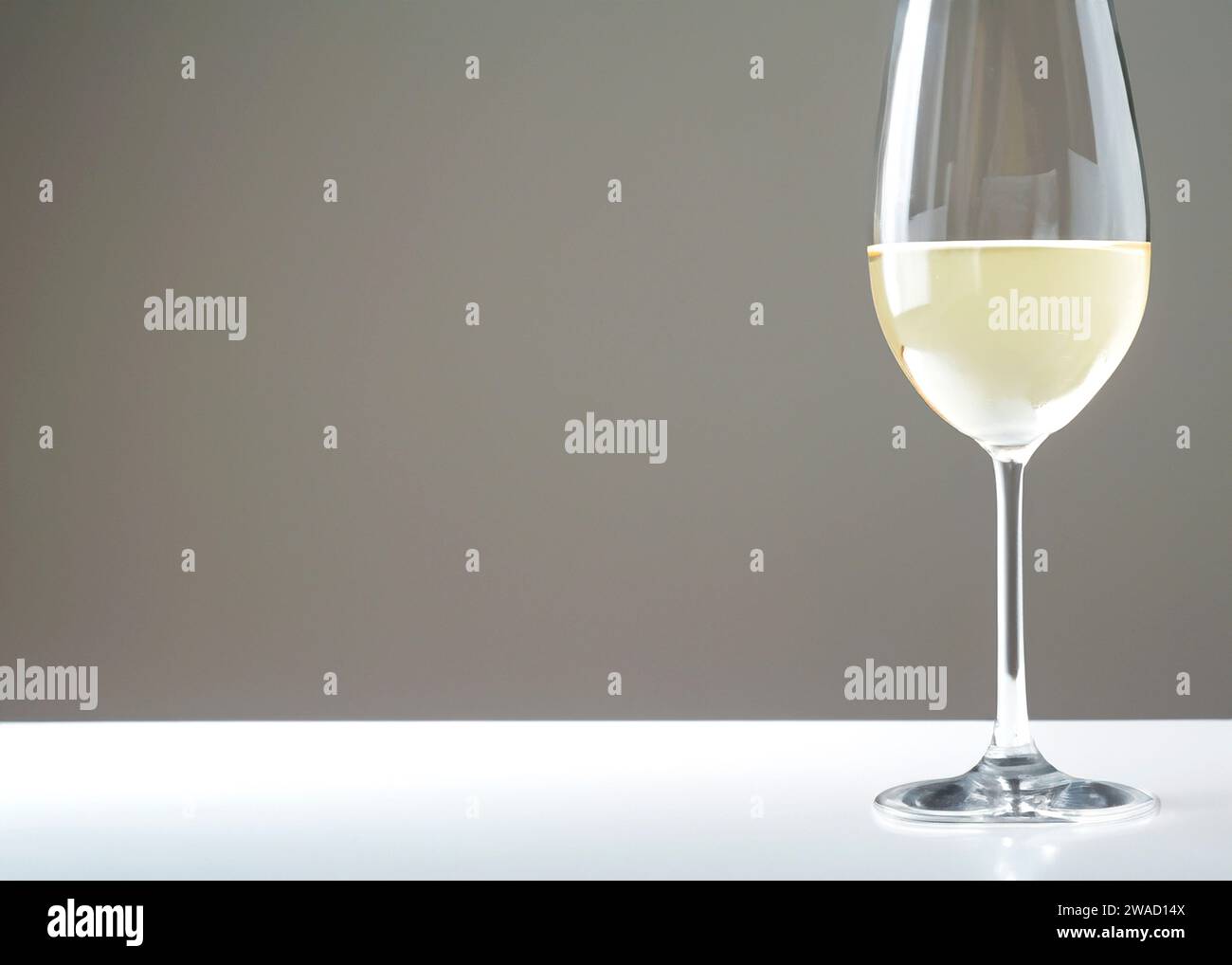 Weißwein im Glas auf weißem Tisch und grauem Hintergrund mit Kopierraum Stockfoto