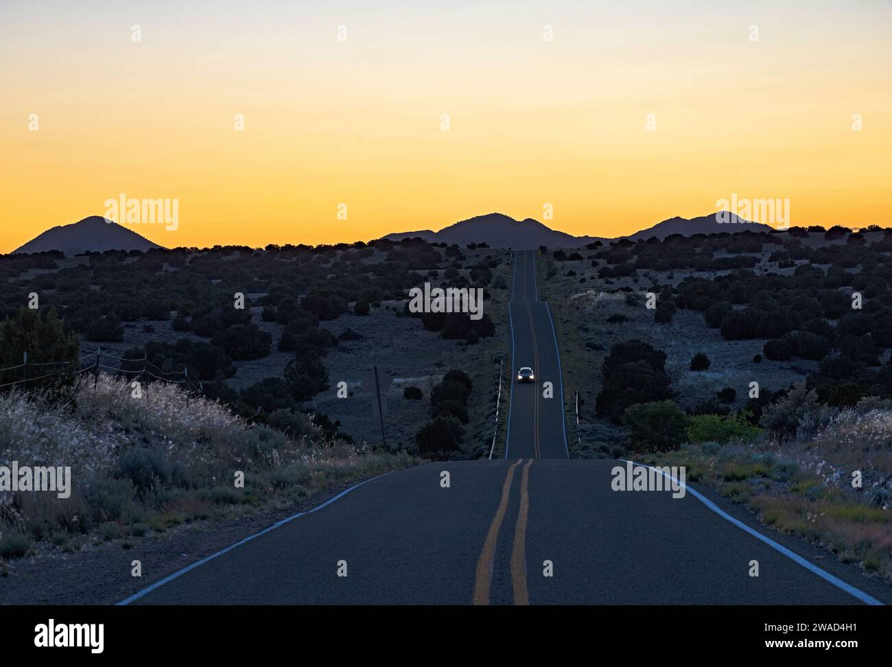 USA, New Mexico, Galisteo, Auto auf der Wüstenstraße in der Abenddämmerung Stockfoto
