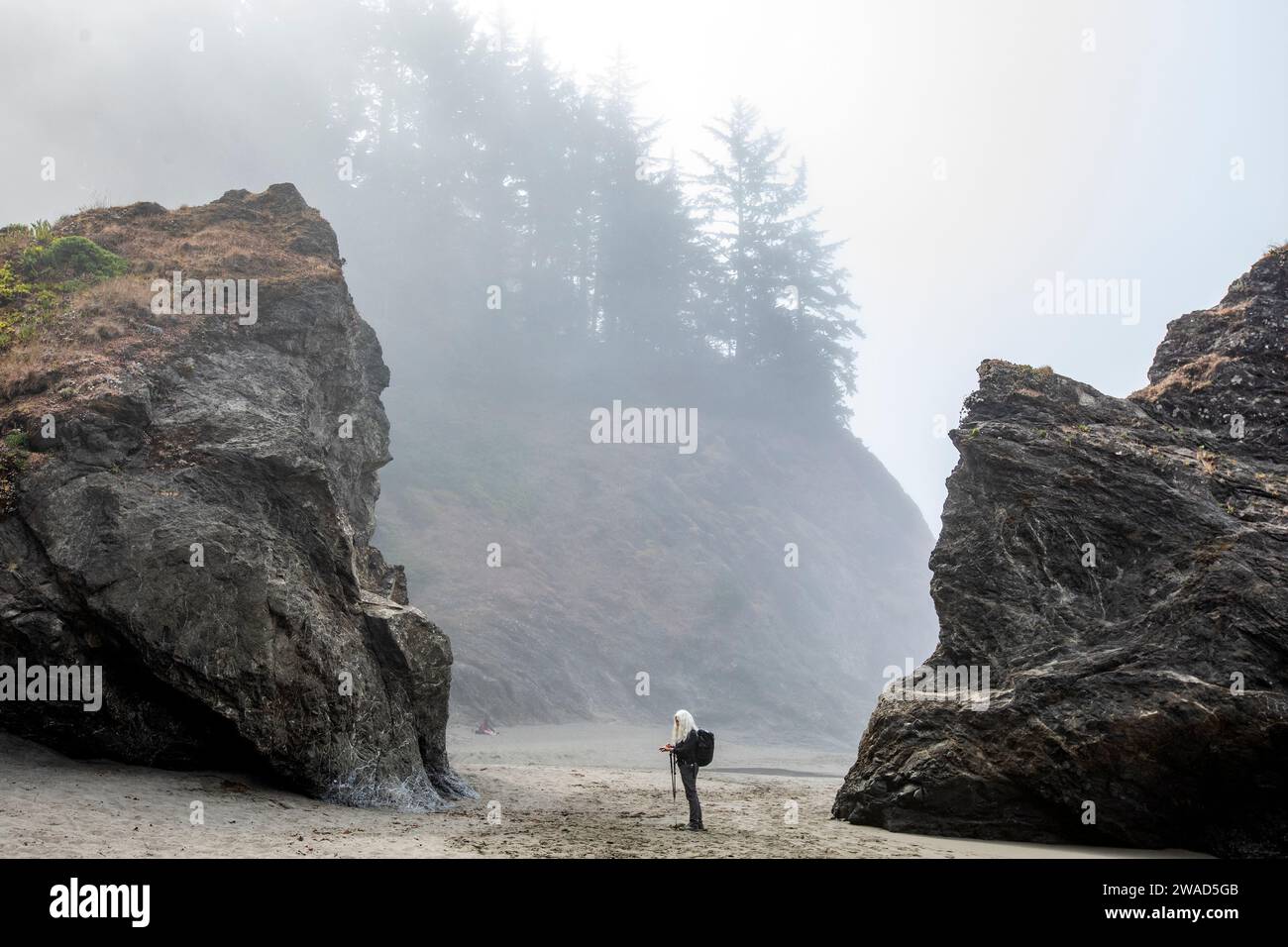 USA, Oregon, Brookings, Senior Frau, die zwischen Felsen am Strand steht Stockfoto