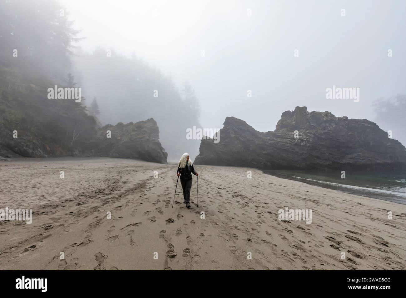 USA, Oregon, Brookings, Senior Woman Wander mit nordic Walking Stöcke am Strand Stockfoto