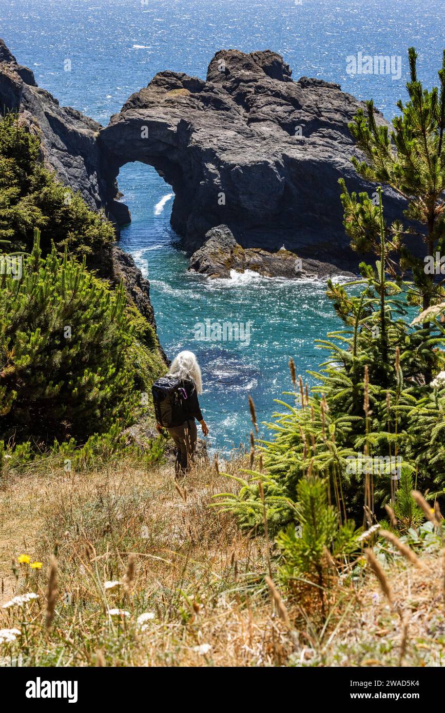 USA, Oregon, Brookings, Senior Woman, Wandern zwischen Felsen über dem Meer Stockfoto