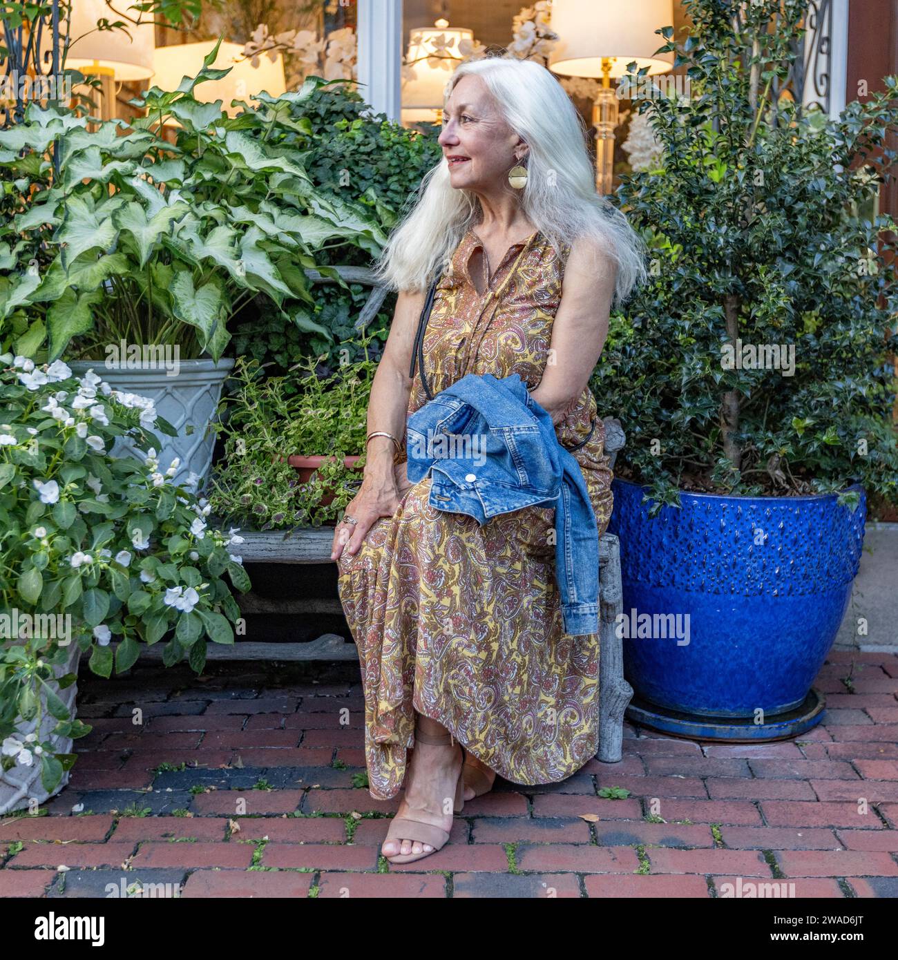 Eine ältere blonde Frau sitzt auf einer Bank im Einkaufsviertel Stockfoto