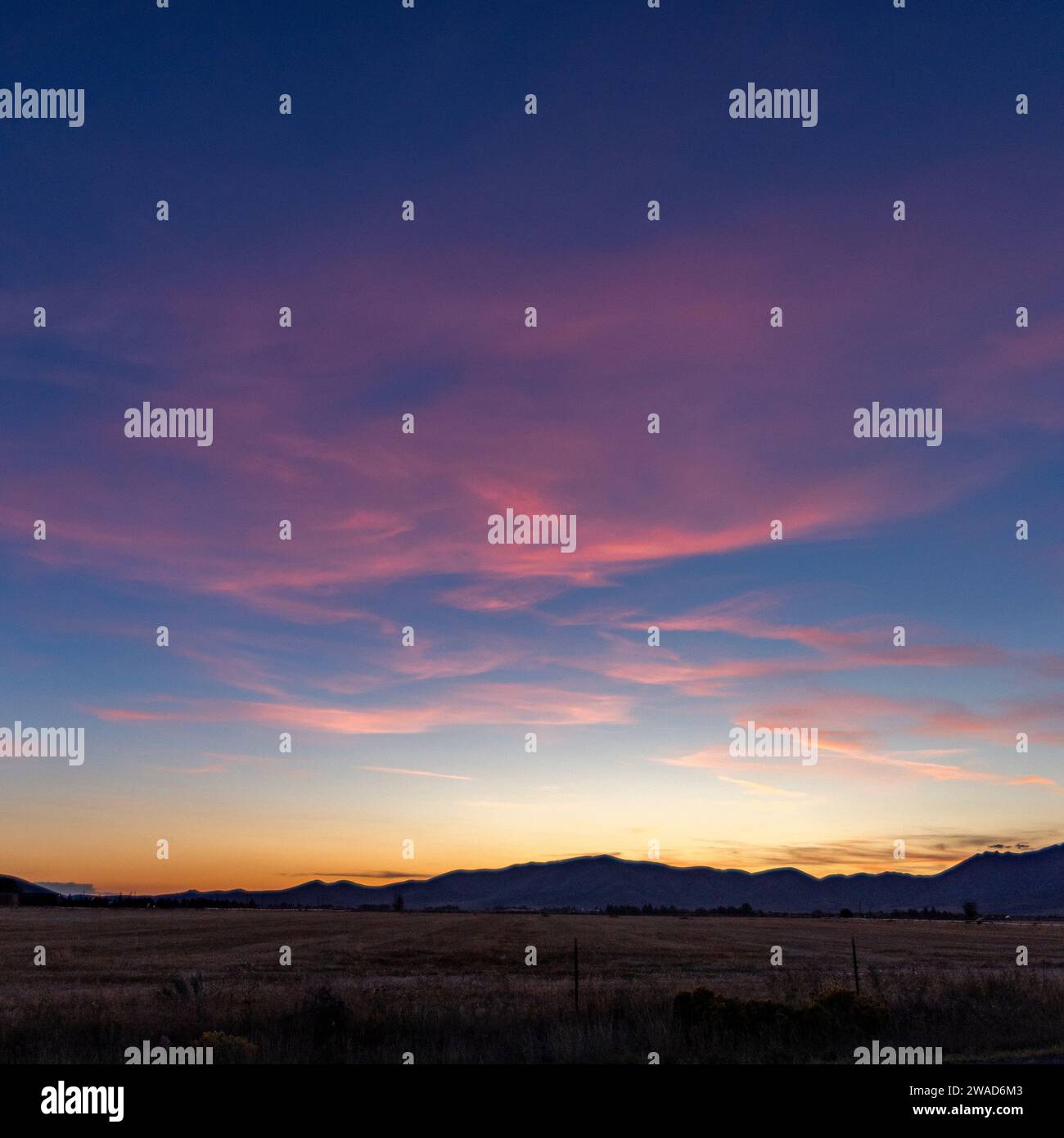 Sonnenuntergangshimmel über landwirtschaftlichen Feldern und Bergen Stockfoto