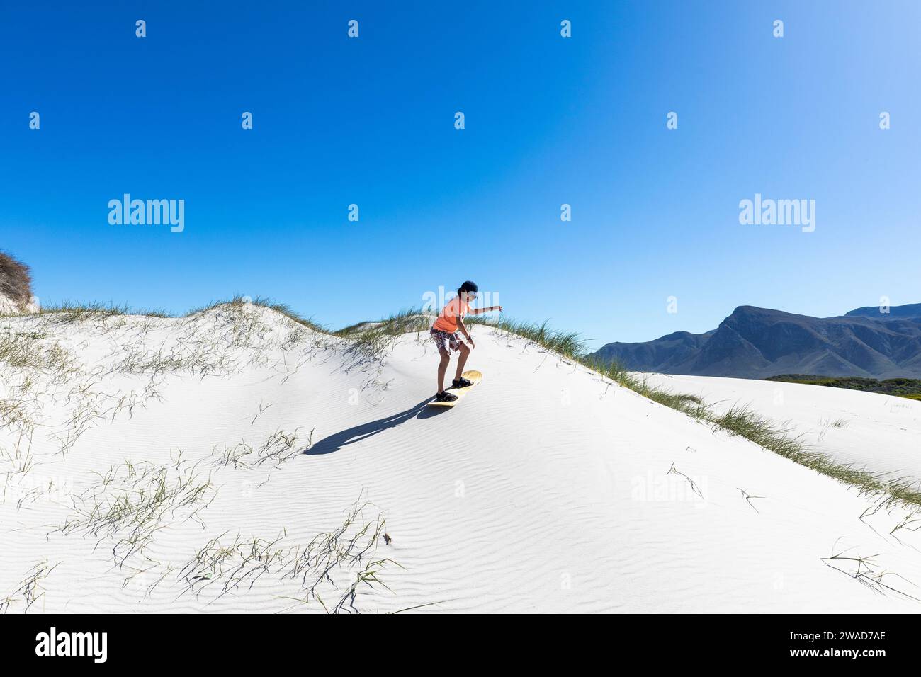Junge (10-11) Sandboarding im Walker Bay Nature Reserve Stockfoto