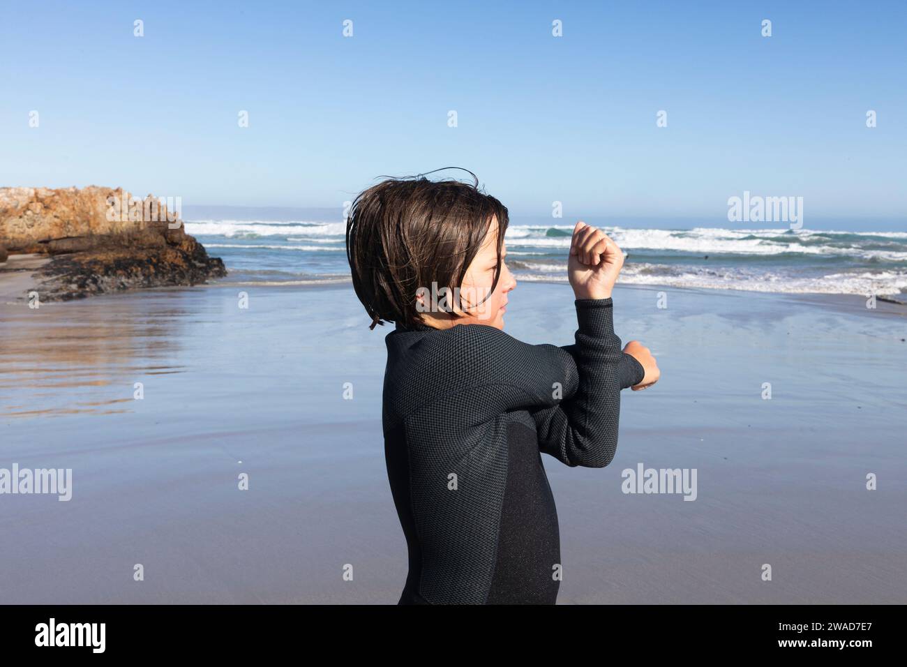 Junge (10-11) streckt sich am Kammabaai Beach Stockfoto