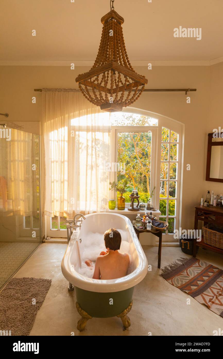 Junge (10-11), der in einer großen Badesuite badet Stockfoto