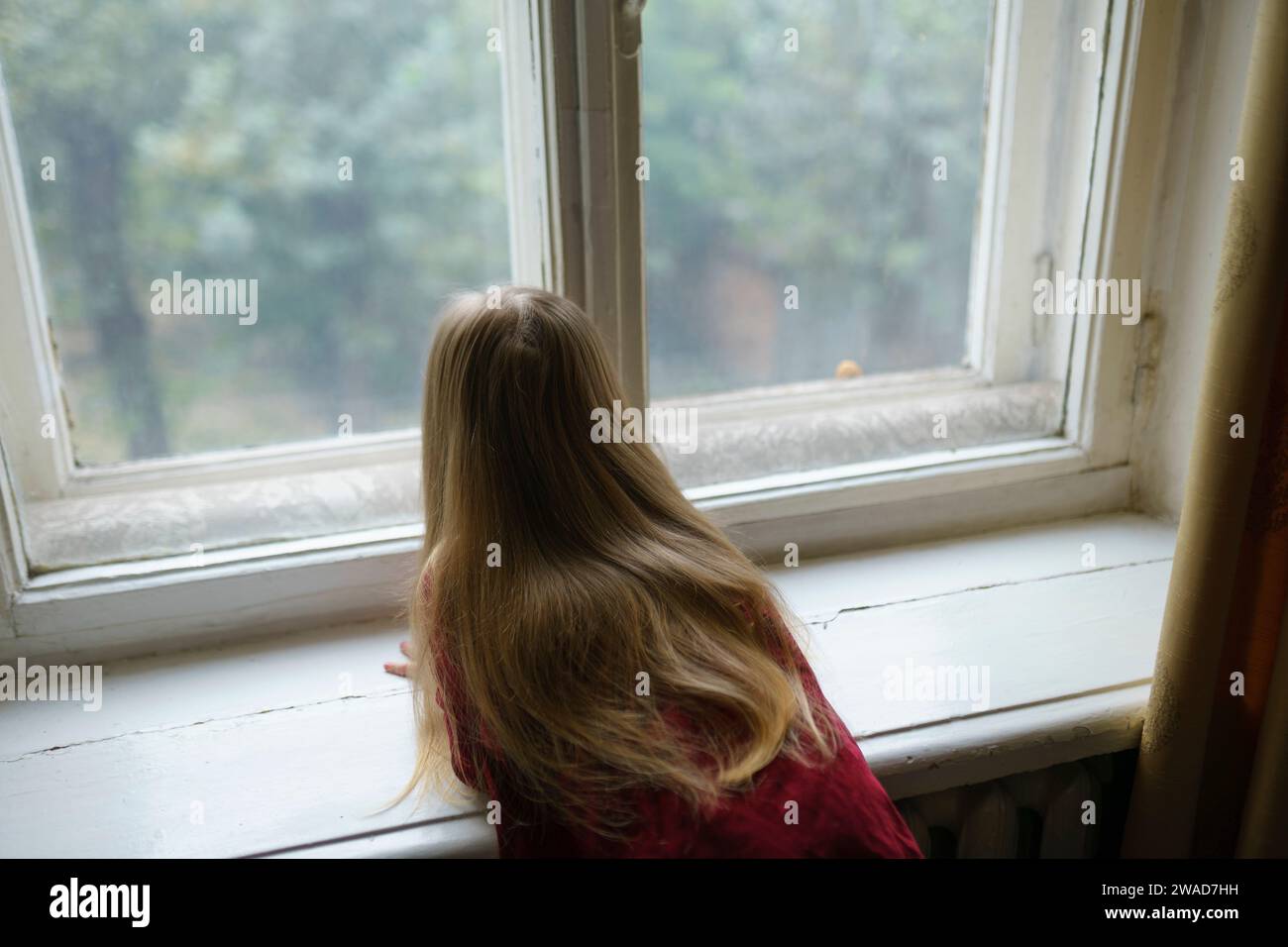 Mädchen (4-5) sieht neugierig durch das Fenster Stockfoto