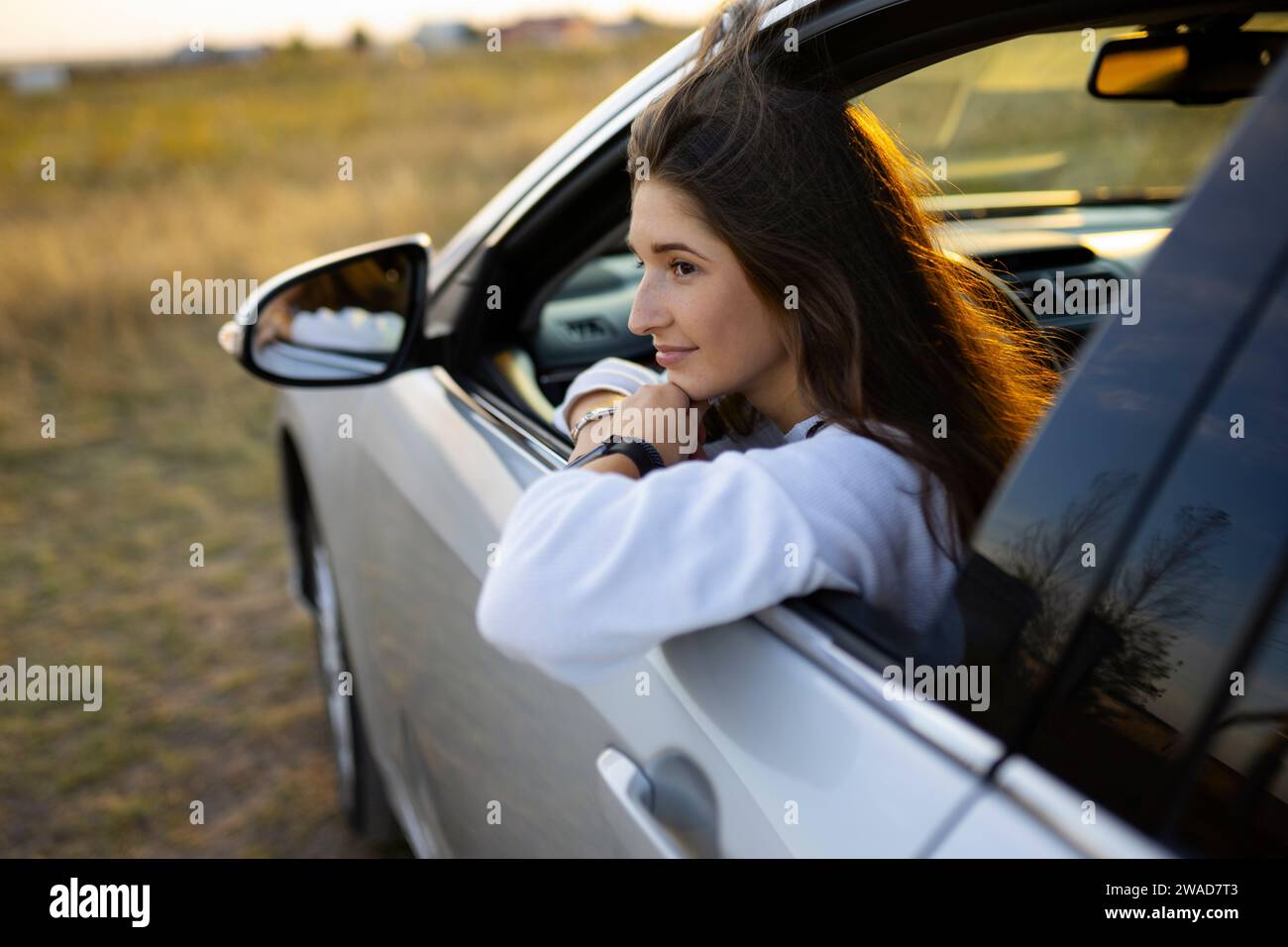 Junge Frau, die durch das Fenster schaut, während sie Auto fährt Stockfoto