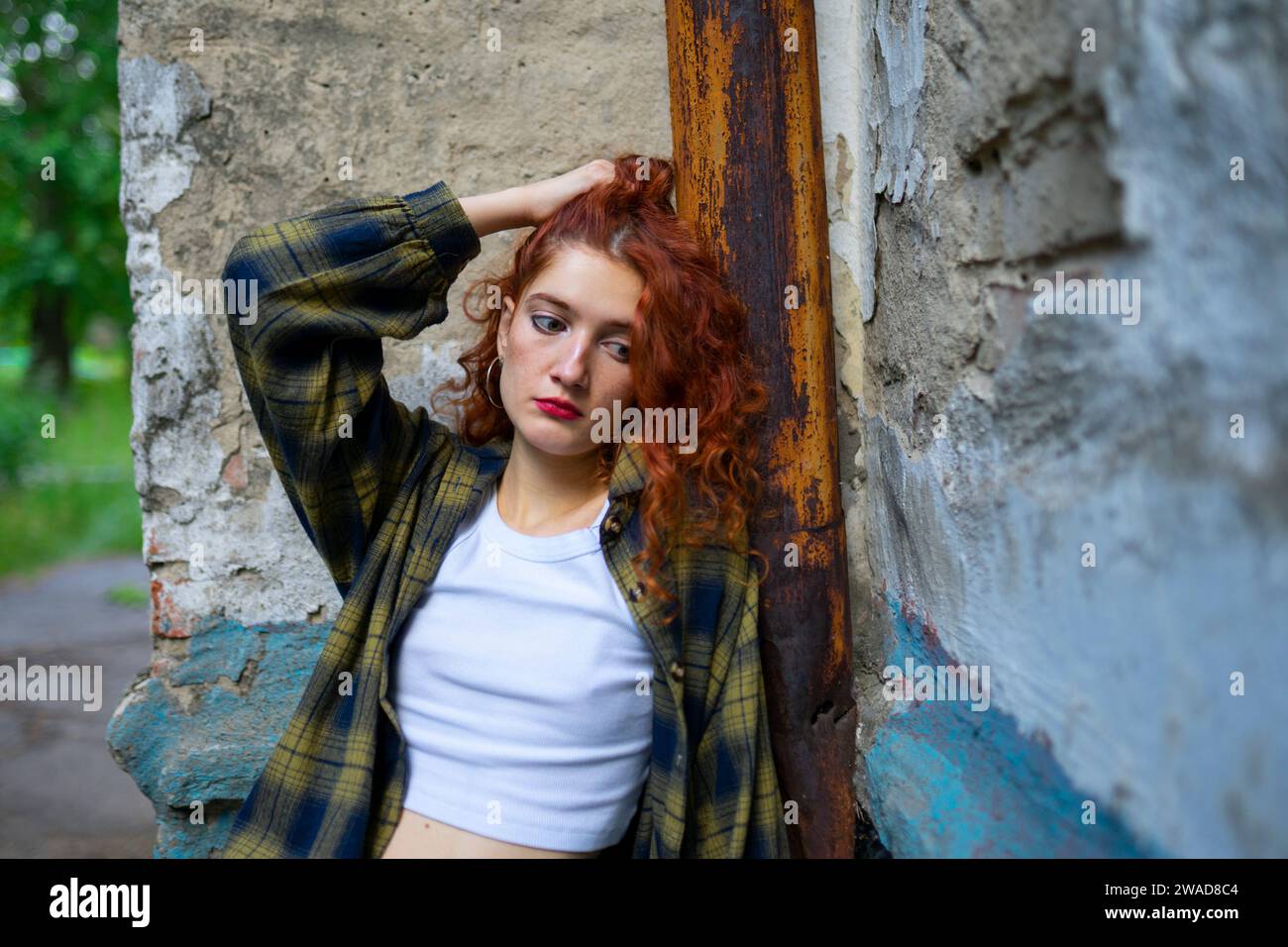 Porträt einer nachdenklichen Frau, die sich an die Gebäudewand lehnt Stockfoto