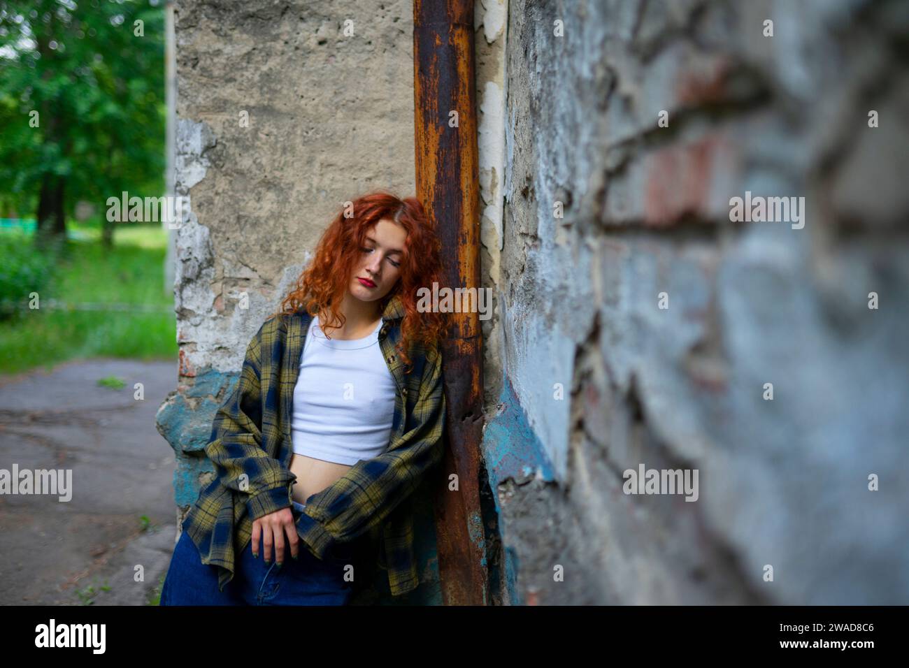 Müde Frau mit geschlossenen Augen, die sich an die Gebäudewand lehnt Stockfoto