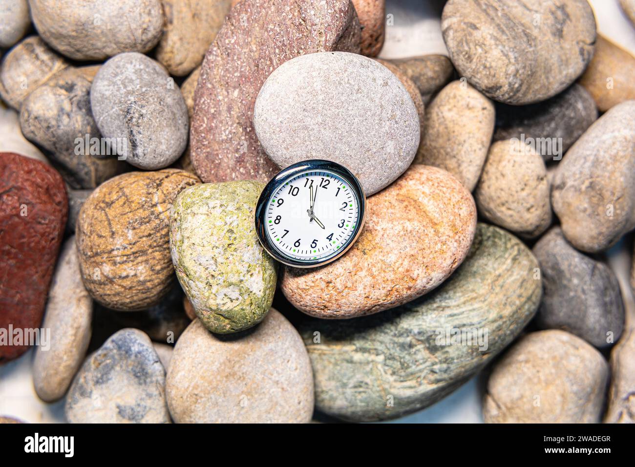 Uhr mit Zeit auf Steinen für das Konzept der Entspannung oder des Vorwärtsbewegens und der Motivation Stockfoto
