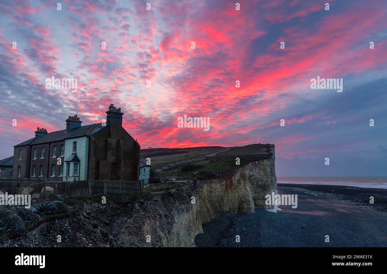 Dramatischer Morgenhimmel über den prekären Cottages am Klippenrand von Birling Gap im Süden der östlichen Küste von Sussex im Südosten Englands Großbritannien Stockfoto