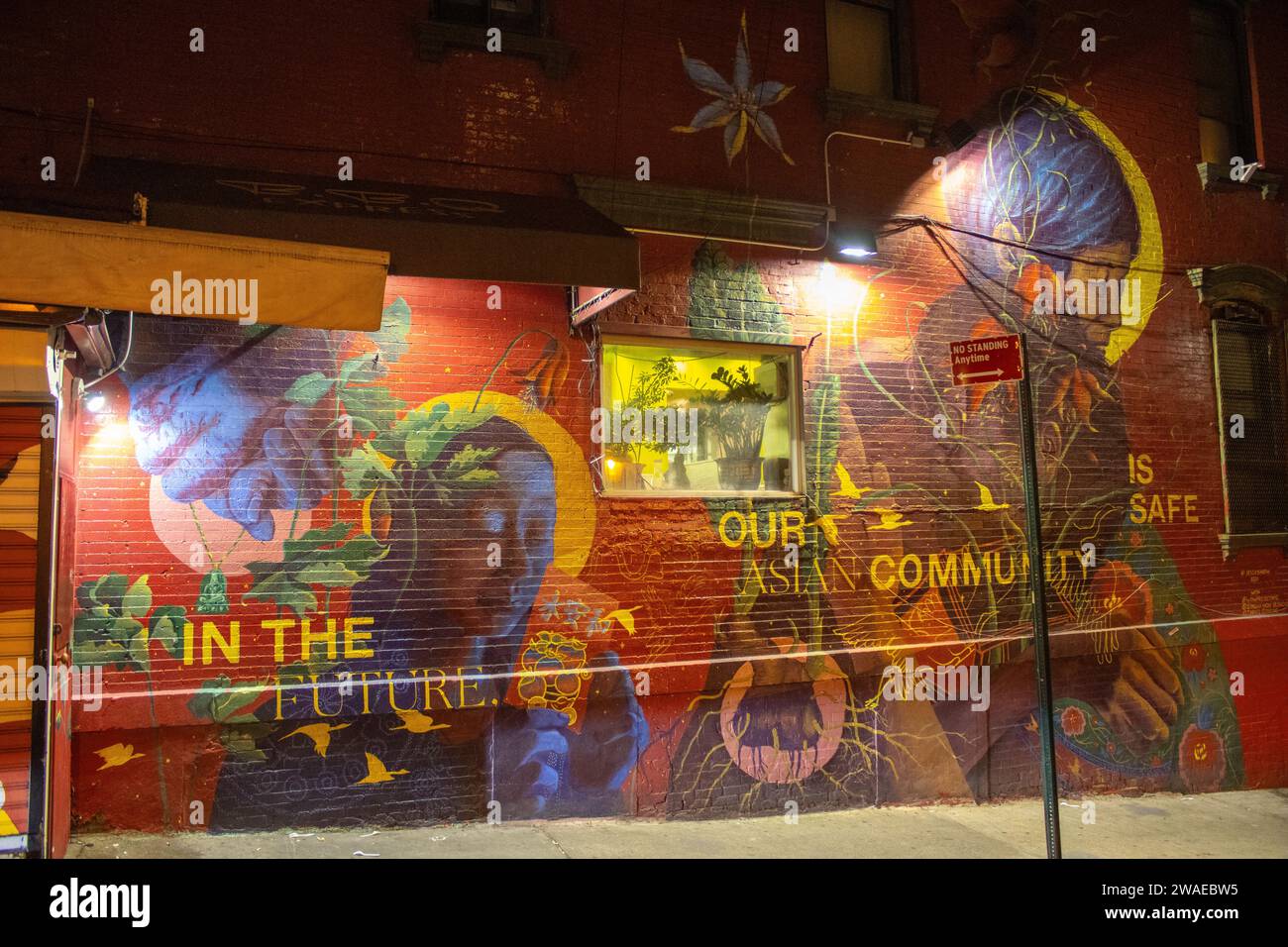 Eine Backsteinmauer eines Gebäudes, bedeckt mit Graffiti, beleuchtet nachts in New York Stockfoto