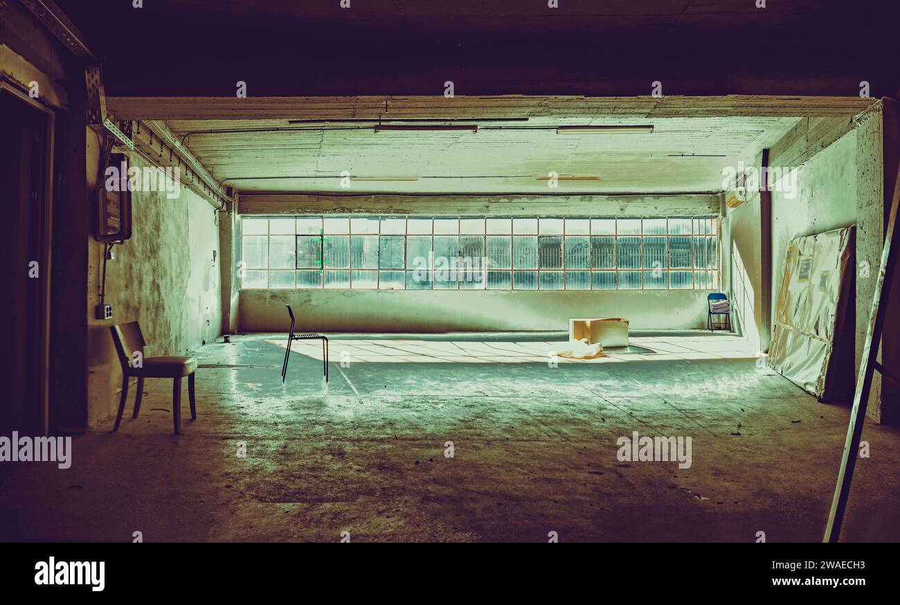 Ein unbewohntes Innenzimmer mit einem Einzelstuhl zum Fenster Stockfoto