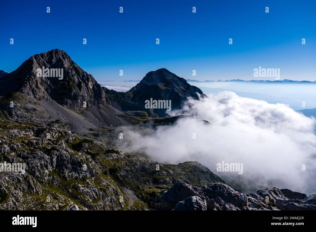 Die Berge Cima dei Lasteri und Piz Galin ragen aus den Wolken, vom Gipfel des Croz dell'Altissimo aus gesehen. Stockfoto