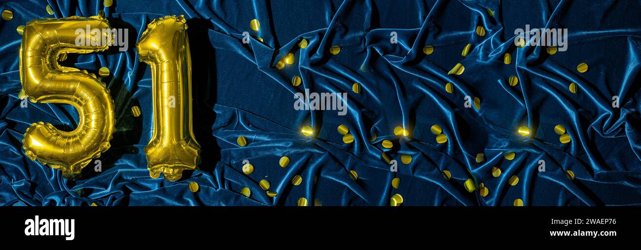 Nummer 51, goldene Folienballonnummer auf blauem Samtgrund mit Konfetti. Geburtstagsgrußkarte, Inschrift 51. Jubiläumsveranstaltung Stockfoto