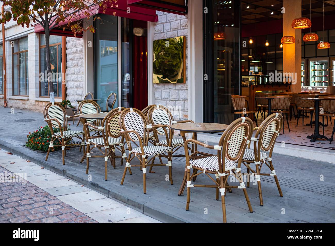 Straßenblick auf eine Kaffeeterrasse mit Tischen und Stühlen. Kostenloser Kaffeetisch. Leerer Kaffee im Freien und Restaurantterrasse an einem Sommertag in Europa Stockfoto