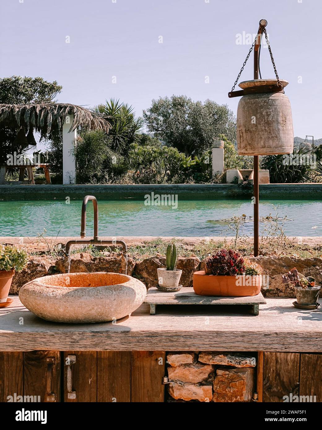 Ein rustikales Waschbecken im Freien mit einem ruhigen Pool im Hintergrund Stockfoto