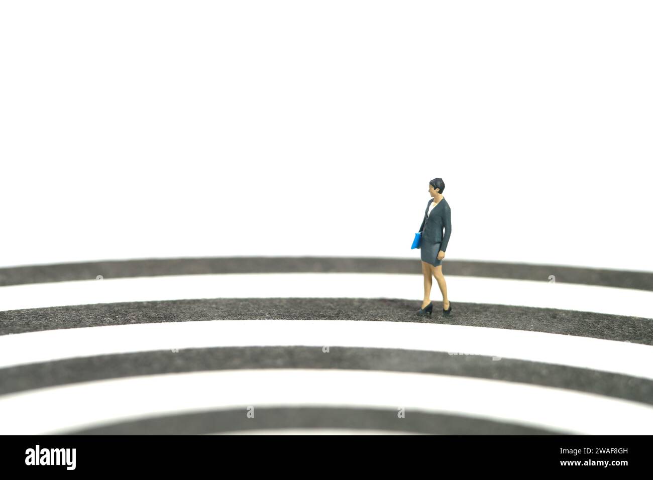 Miniatur Menschen Spielzeug Figur Fotografie. Konzept für den Karriereweg. Eine Geschäftsfrau, die auf Dartscheibe geht. Isoliert auf weißem Hintergrund. Bildfoto Stockfoto