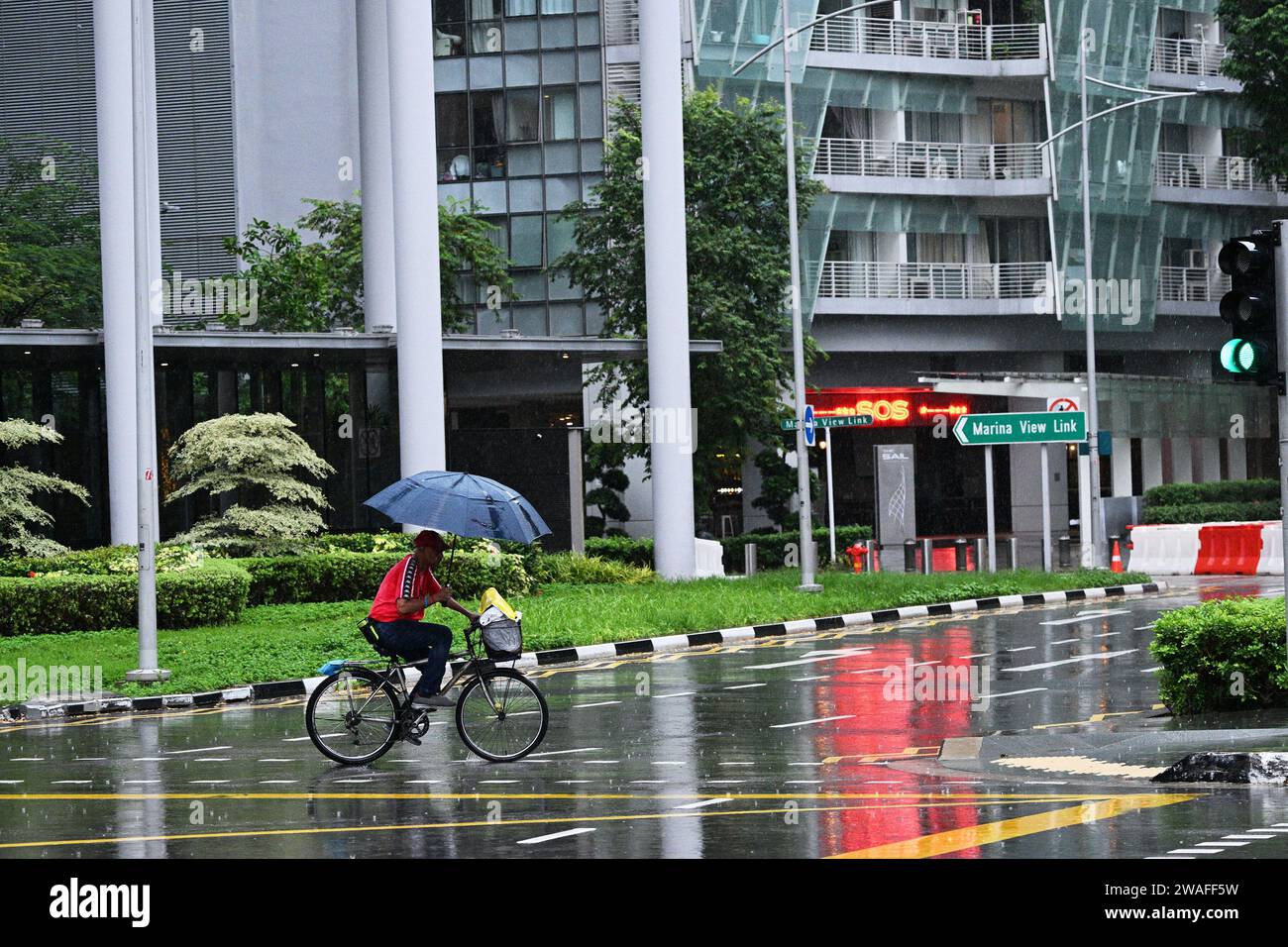 Singapur. Januar 2024. Ein Mann, der einen Schirm hält, reitet im Regen in Singapur, 4. Januar 2024. Quelle: Dann Chih Wey/Xinhua/Alamy Live News Stockfoto