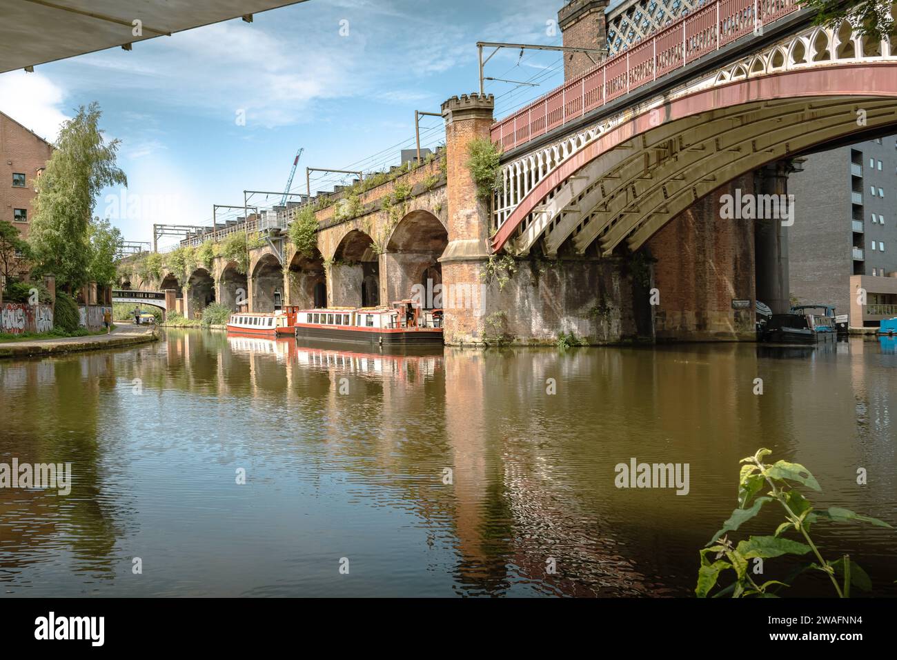 Der beschauliche Manchester Bridgwater Canal, flankiert von einer historischen Brücke mit mehreren Bögen. Urbaner Charme in ruhiger Lage am Wasser. Reisetourismuskonzept Stockfoto