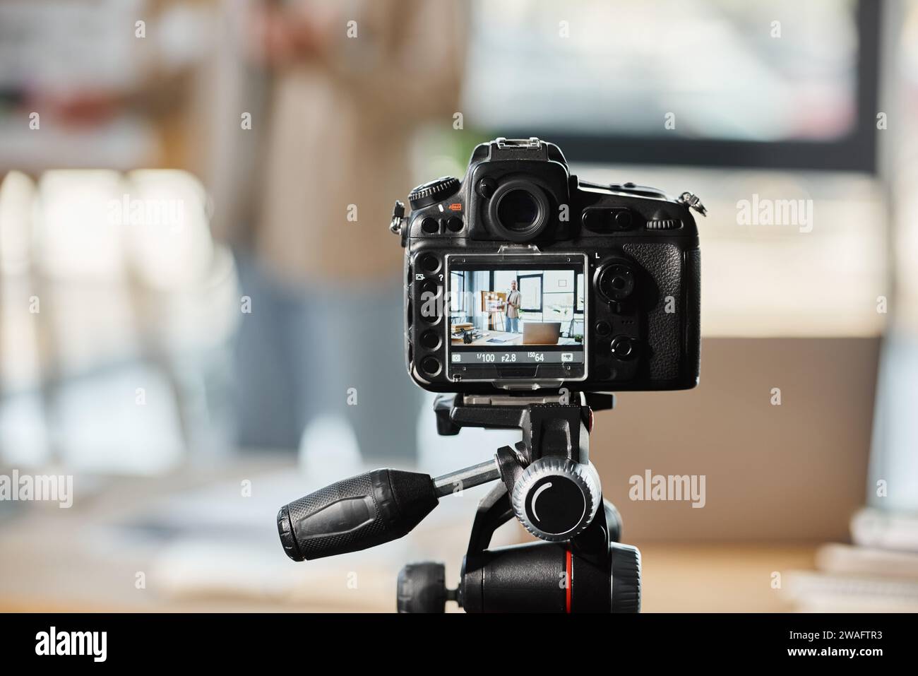 Selektiver Fokus auf Digitalkamera in der Nähe von verschwommenem Unternehmer, der Video-Blog in modernen Büros aufnimmt Stockfoto