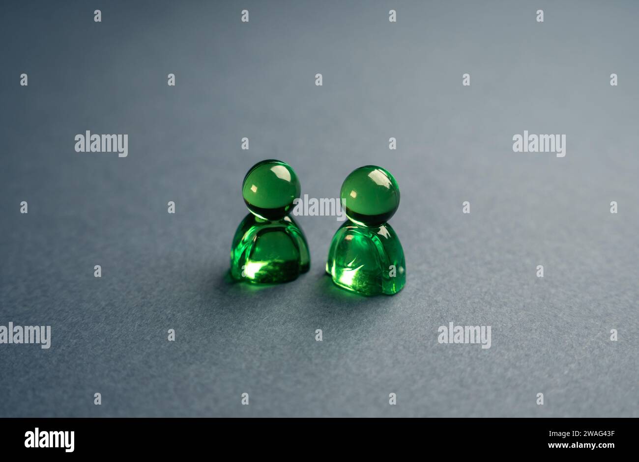 Zwei grüne Glasfiguren von Menschen. Konzept der Kommunikation und Geschäftsbeziehung. Unterstützung, Zusammenarbeit und Zusammenarbeit. Ein Meeting. Freundlich Stockfoto