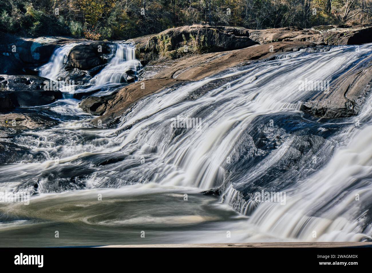 Rauschende Wasserfälle im High Falls State Park in Georgia am Fluss in landschaftlich reizvoller Natur mit herbstlichem Laub im Hintergrund Stockfoto