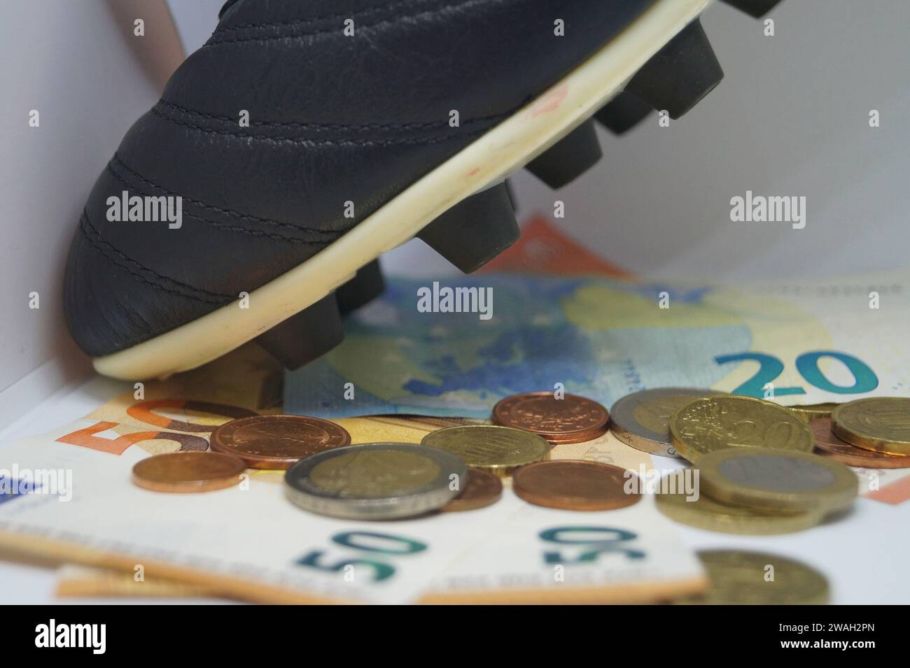Fußballschuh mit Euro, symbolisches Bild des Profi-Fußballs Stockfoto