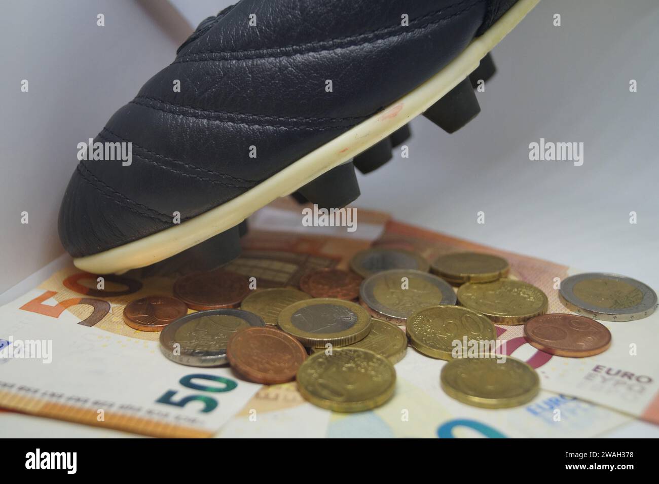 Fußballschuh mit Euro, symbolisches Bild des Profi-Fußballs Stockfoto