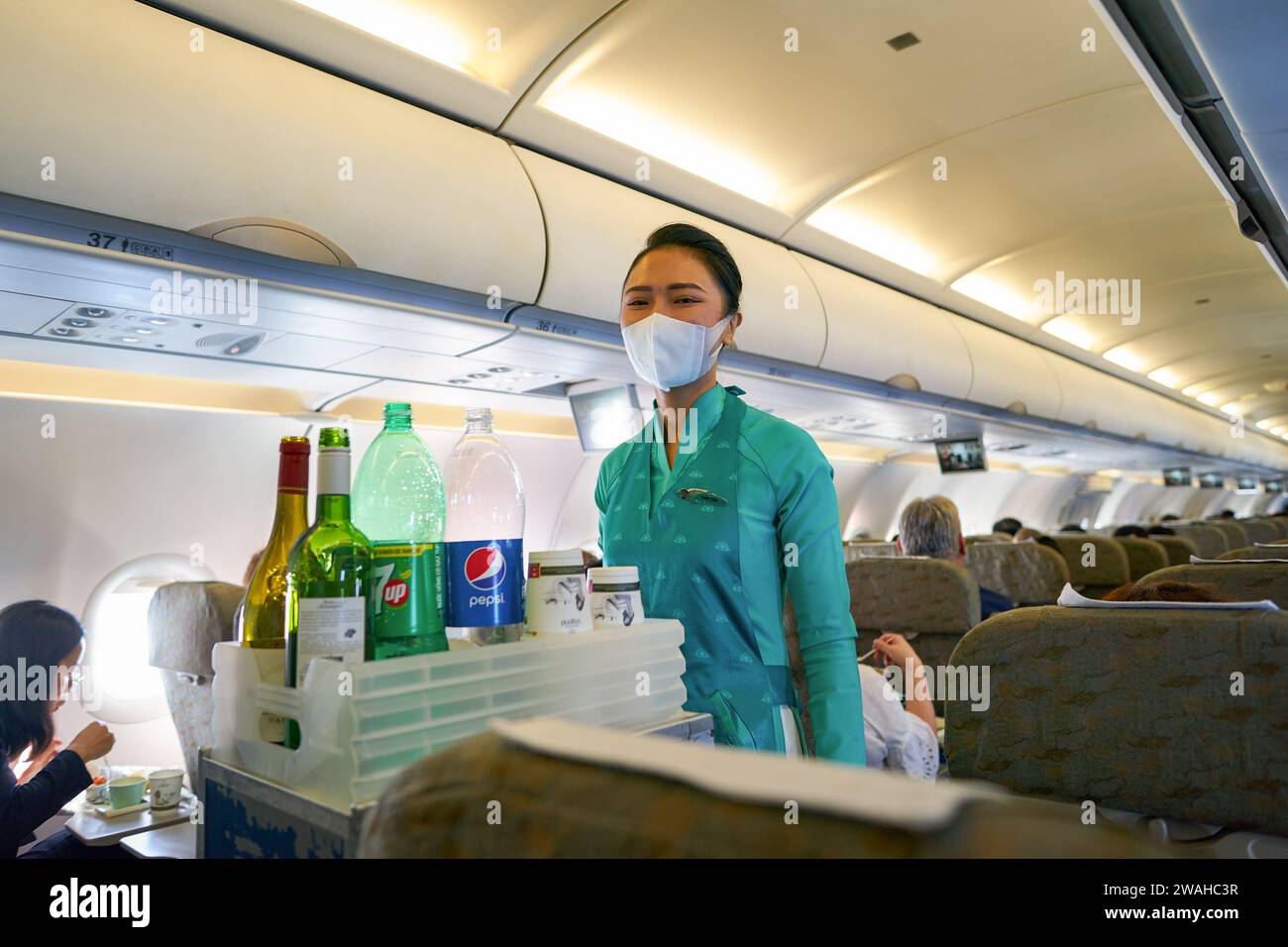 HO-CHI-MINH-STADT, VIETNAM - 24. MÄRZ 2023: Flugbegleiter von Vietnam Airlines in Uniform servieren den Passagieren Getränke an Bord des Airbus A321. Stockfoto