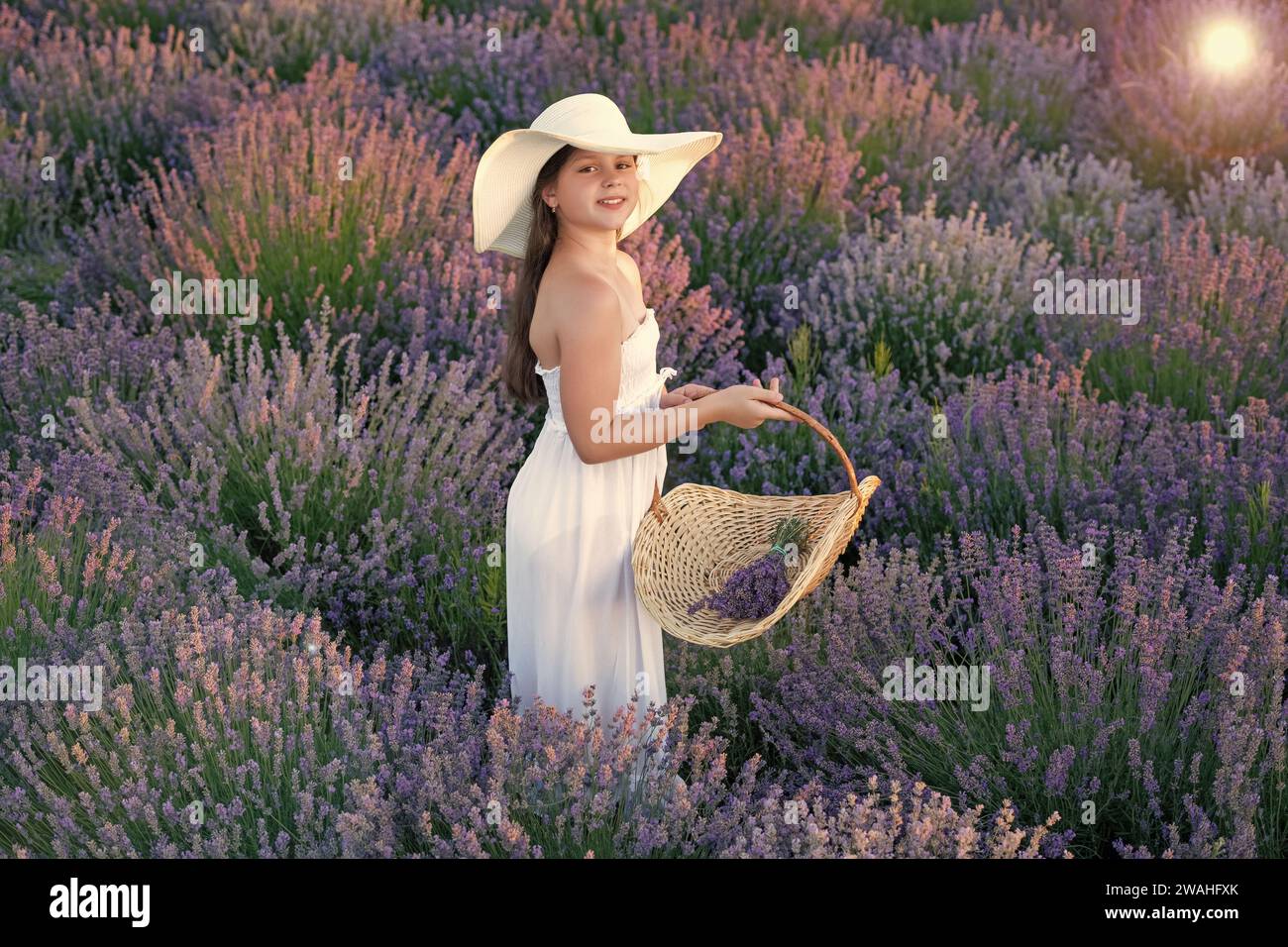 Teenager lächeln mit Lavendel im Feld. Teenager-Mädchen mit Lavendelblume, die auf dem Feld steht. Teenager mit Lavendel und Blumenstrauß. Teenager Stockfoto