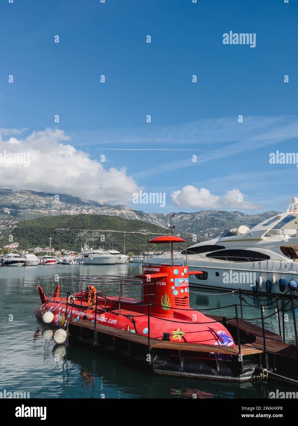 Budva, Montenegro - 17. august 2023: Rotes Exkursions-U-Boot liegt am Pier vor der Kulisse der Berge vor Stockfoto