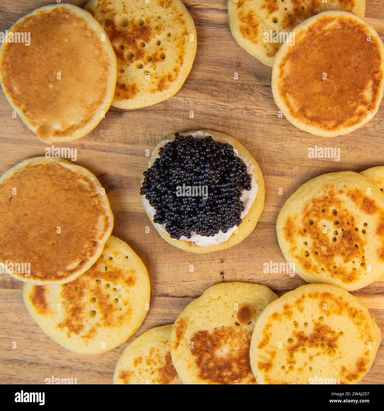 Blinis mit schwarzem Kaviar und Frischkäse, auf festlichem Gericht, Mini-Pfannkuchen, eine elegante Vorspeise Stockfoto