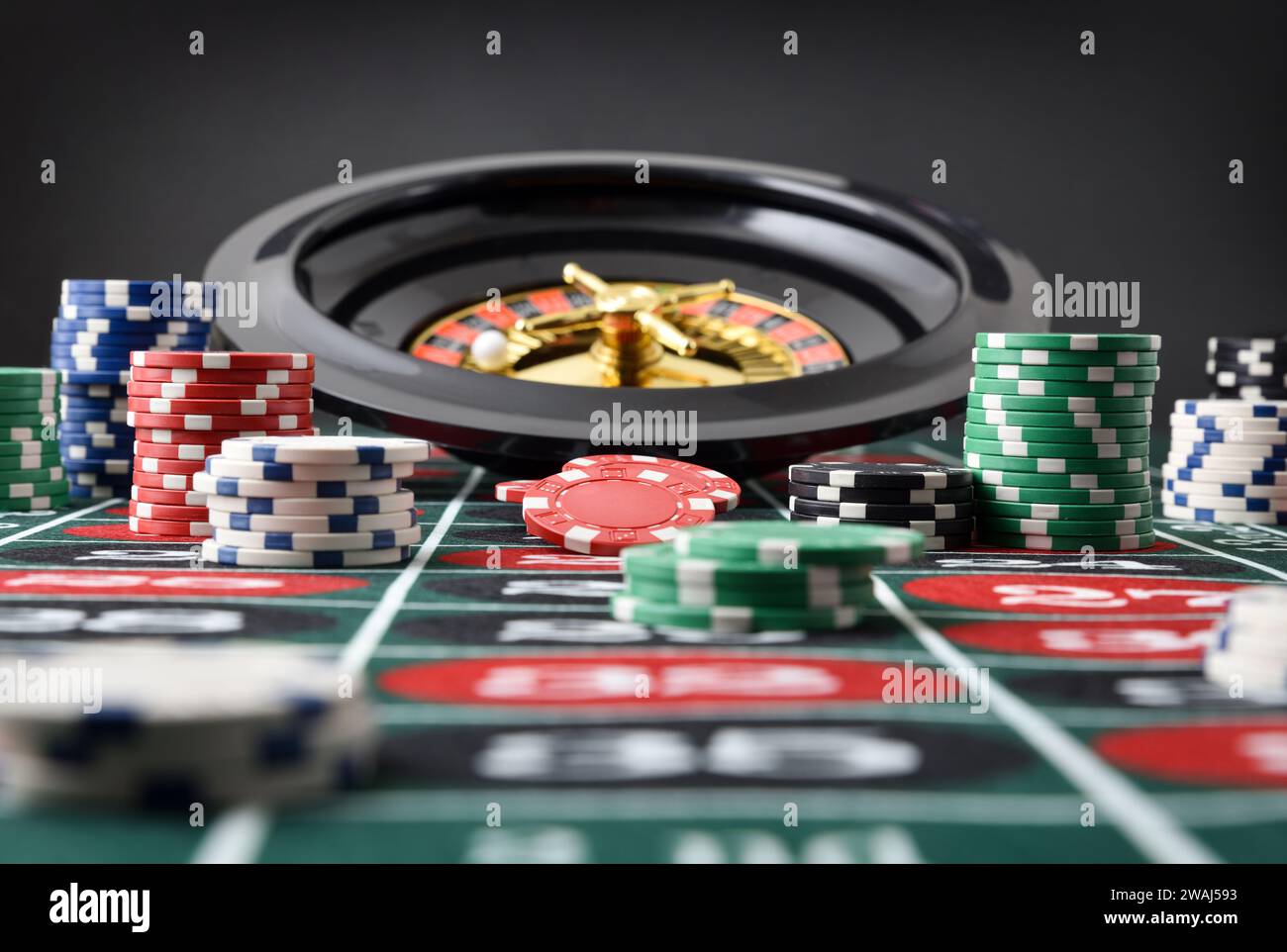 Detail des Roulette-Spieltisches mit Stapeln von Wettchips und Roulette mit isoliertem schwarzem Hintergrund. Vorderansicht. Stockfoto