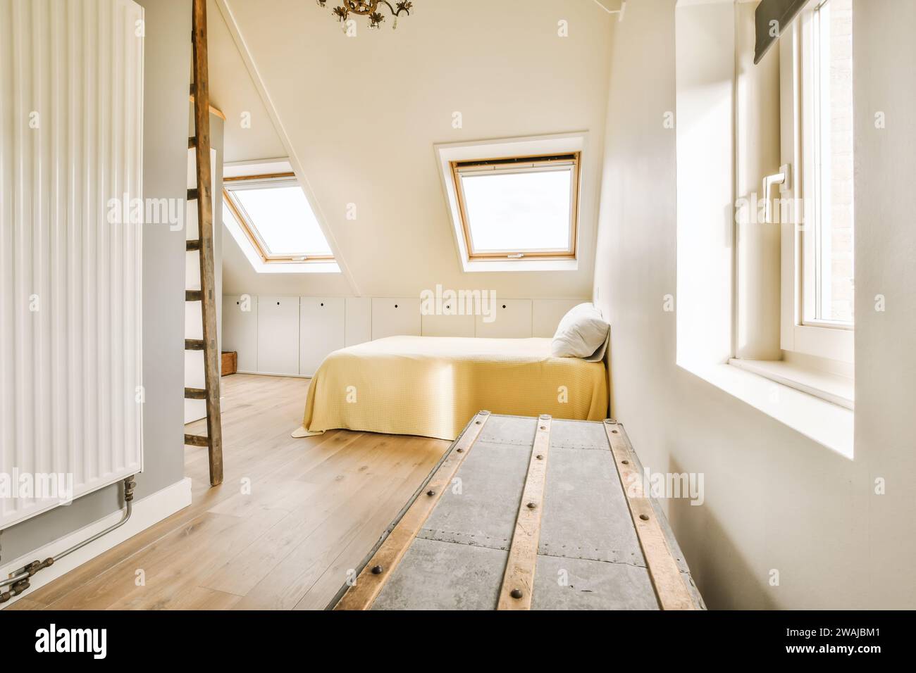 Innenraum des geräumigen Dachgeschoss-Schlafzimmers mit komfortablem Bett und Holzkiste im Loft-Apartment Stockfoto