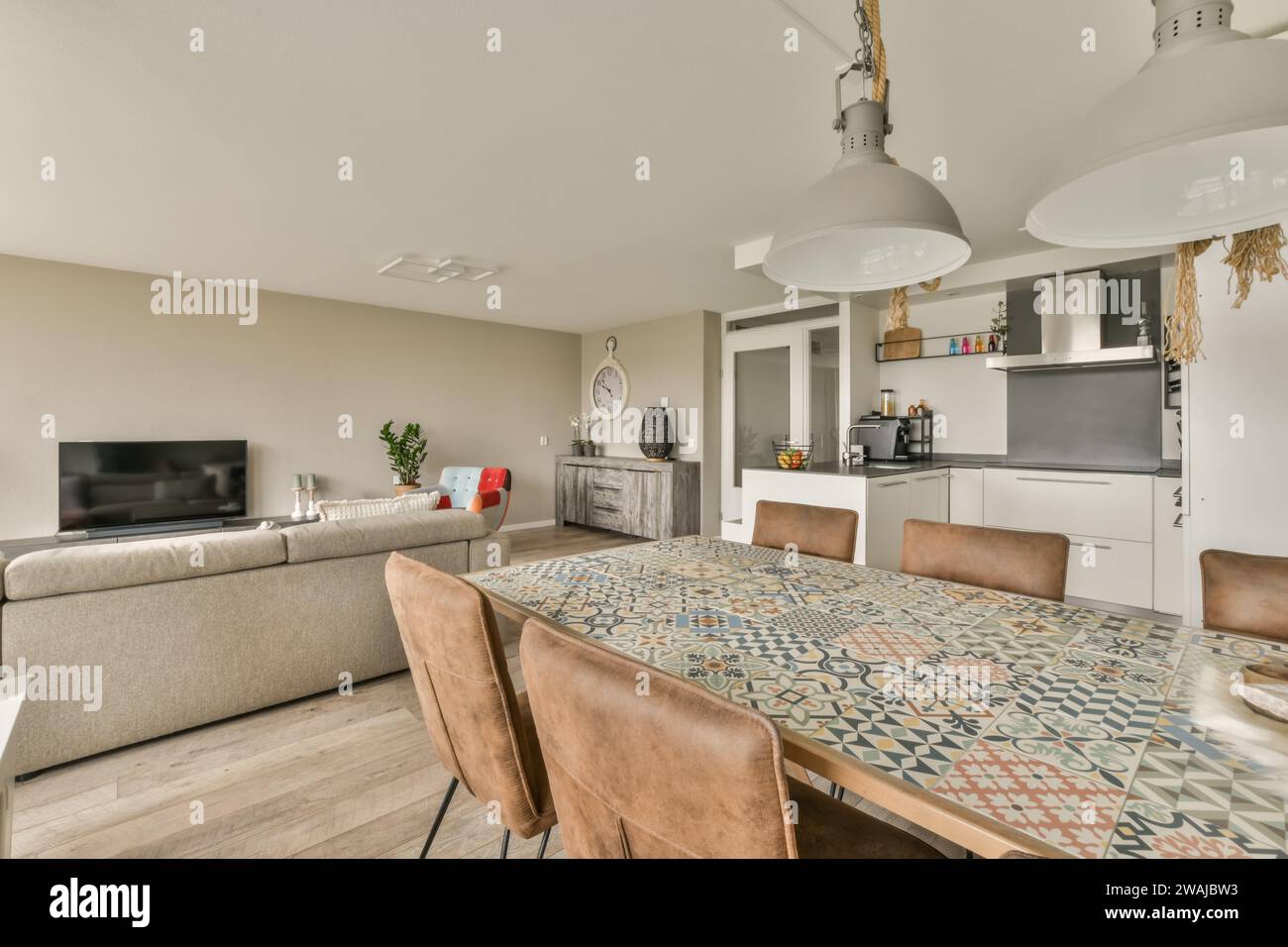 Holztisch und -Stühle im modernen Esszimmer des luxuriösen Apartments mit Wohnzimmer und Küche im Hintergrund Stockfoto