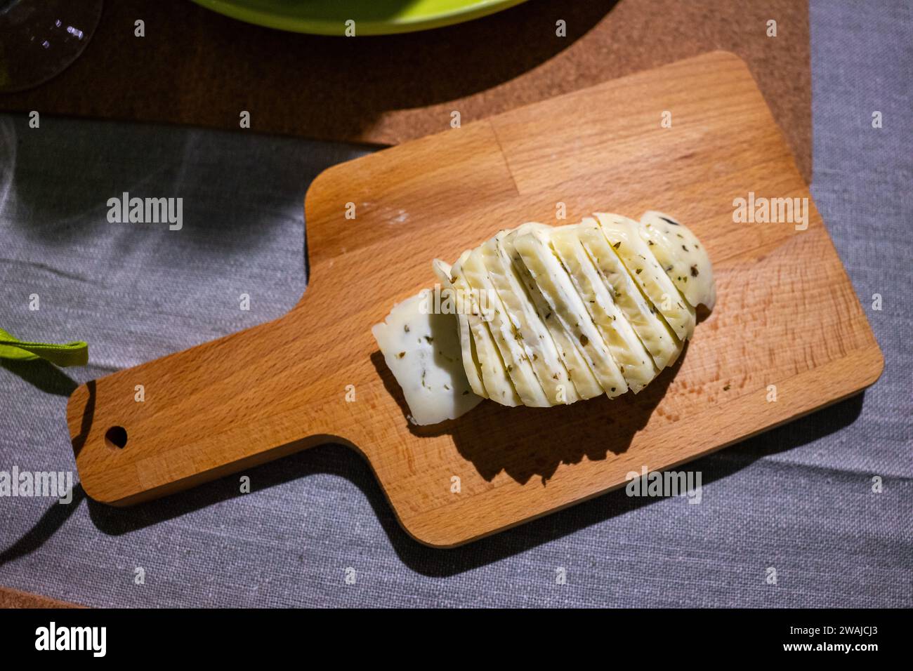 In Scheiben geschnittener portugiesischer Käse mit Oregano auf einem hölzernen Schneidebrett. Stockfoto