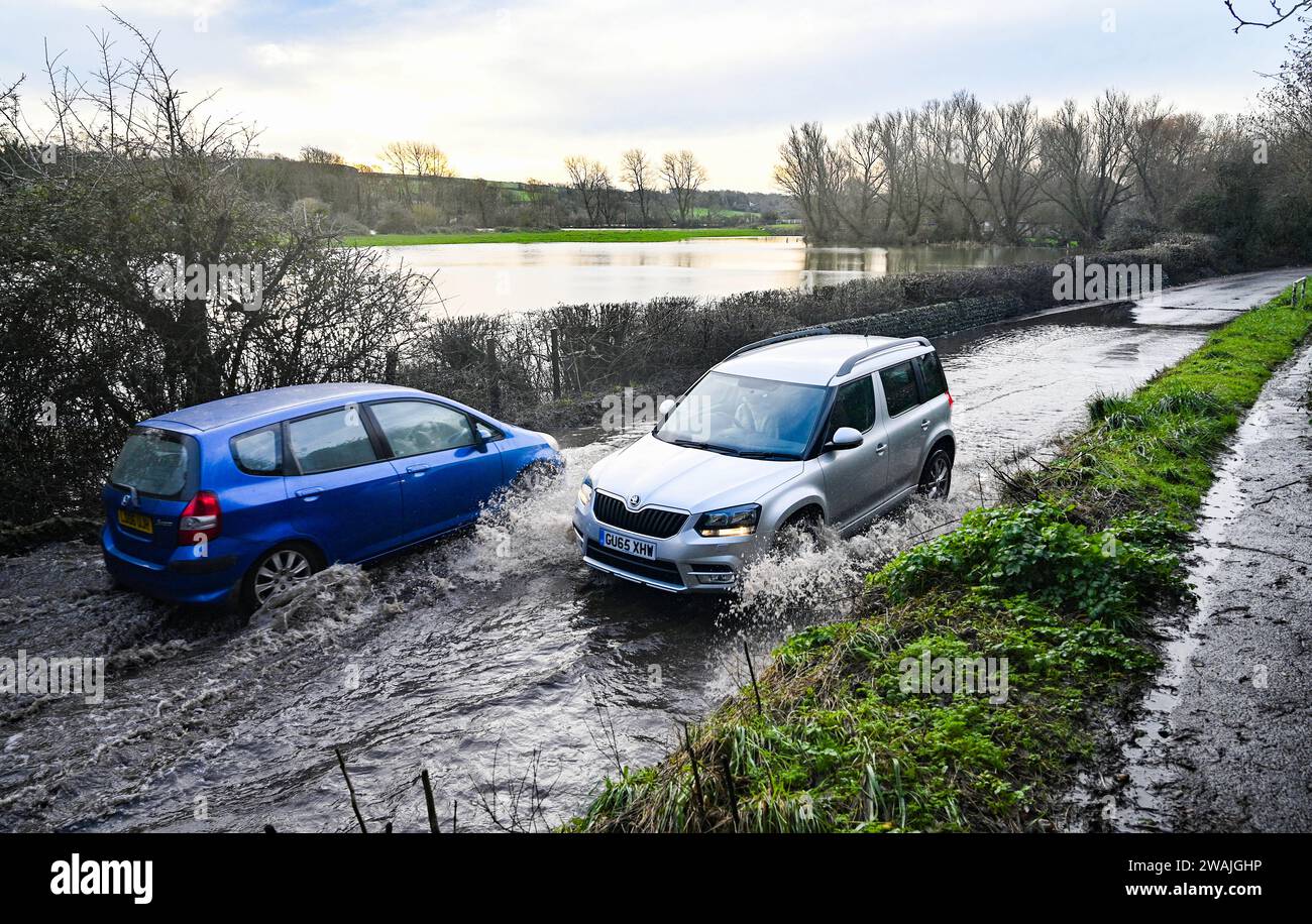 Alfriston, Sussex UK 5. Januar 2024 - der Verkehr durchquert Hochwasser auf den Straßen um das Dorf Alfriston in East Sussex nach einer weiteren Nacht mit starkem Regen und über 300 Hochwasser- und Wetterwarnungen im ganzen Land: Credit Simon Dack / Alamy Live News Stockfoto