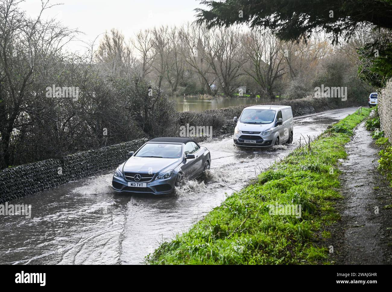 Alfriston, Sussex UK 5. Januar 2024 - der Verkehr durchquert Hochwasser auf den Straßen um das Dorf Alfriston in East Sussex nach einer weiteren Nacht mit starkem Regen und über 300 Hochwasser- und Wetterwarnungen im ganzen Land: Credit Simon Dack / Alamy Live News Stockfoto