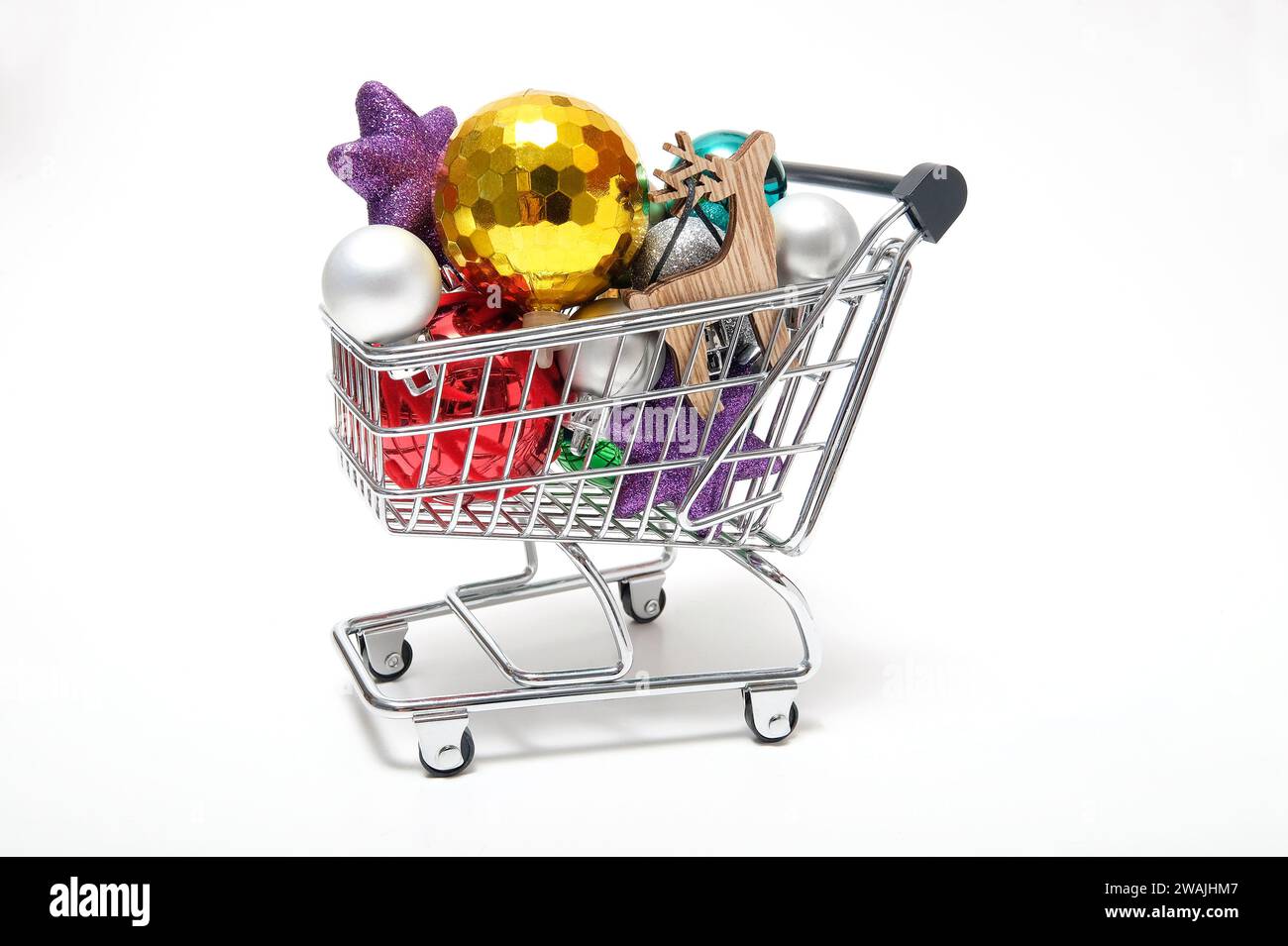 weihnachtskugeln im Miniatur-Supermarktwagen auf weißem Hintergrund Stockfoto