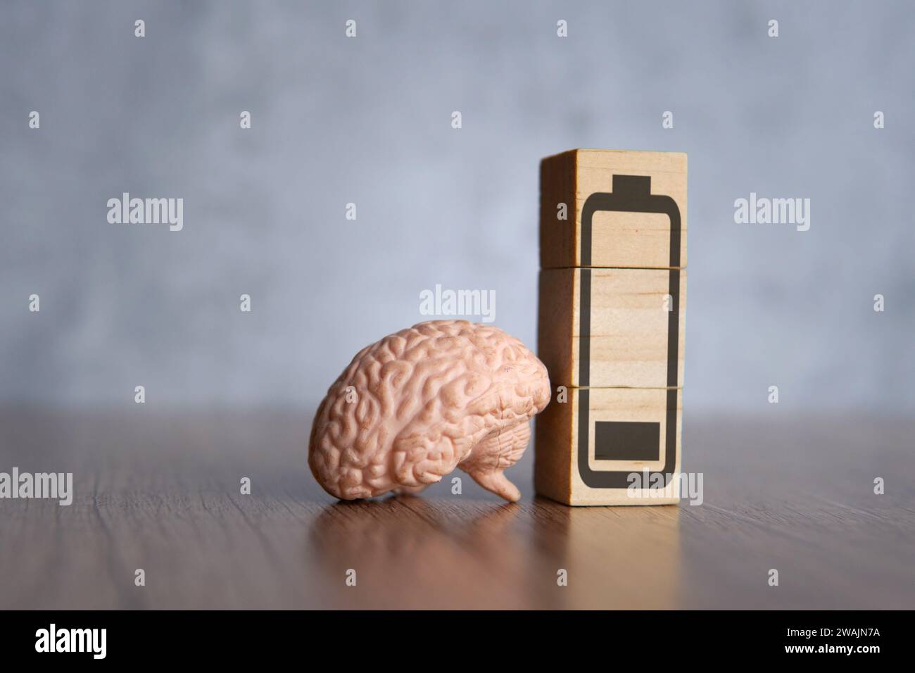 Nahaufnahme von Gehirn- und Holzblöcken mit Energiesparbatterie. Erschöpftes, müdes und Burnout-Konzept. Stockfoto