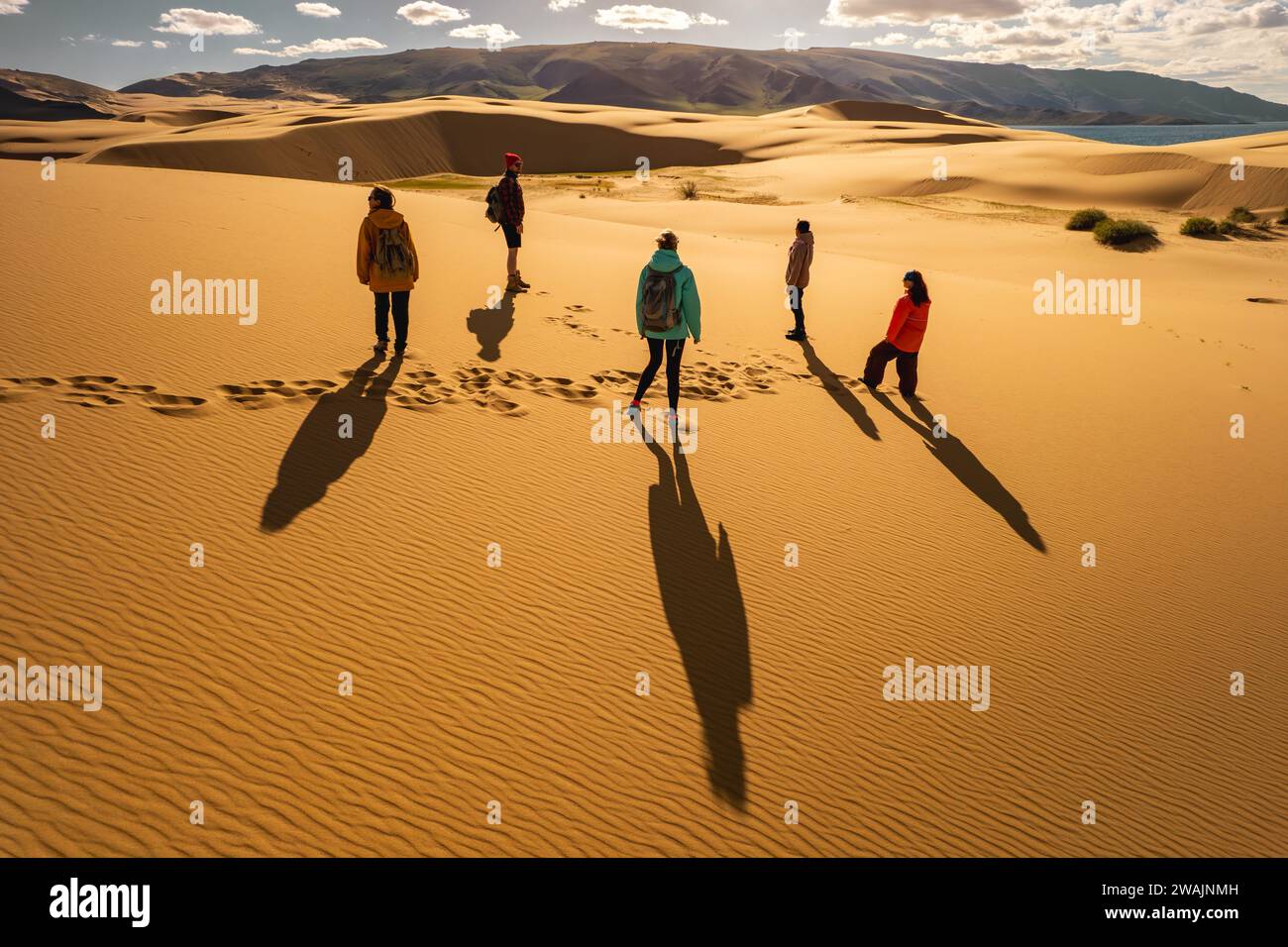 Verschiedene Gruppen von Touristen stehen an den Sonnenuntergangsdünen. Menschen und Silhouetten vor Sanddünen Stockfoto