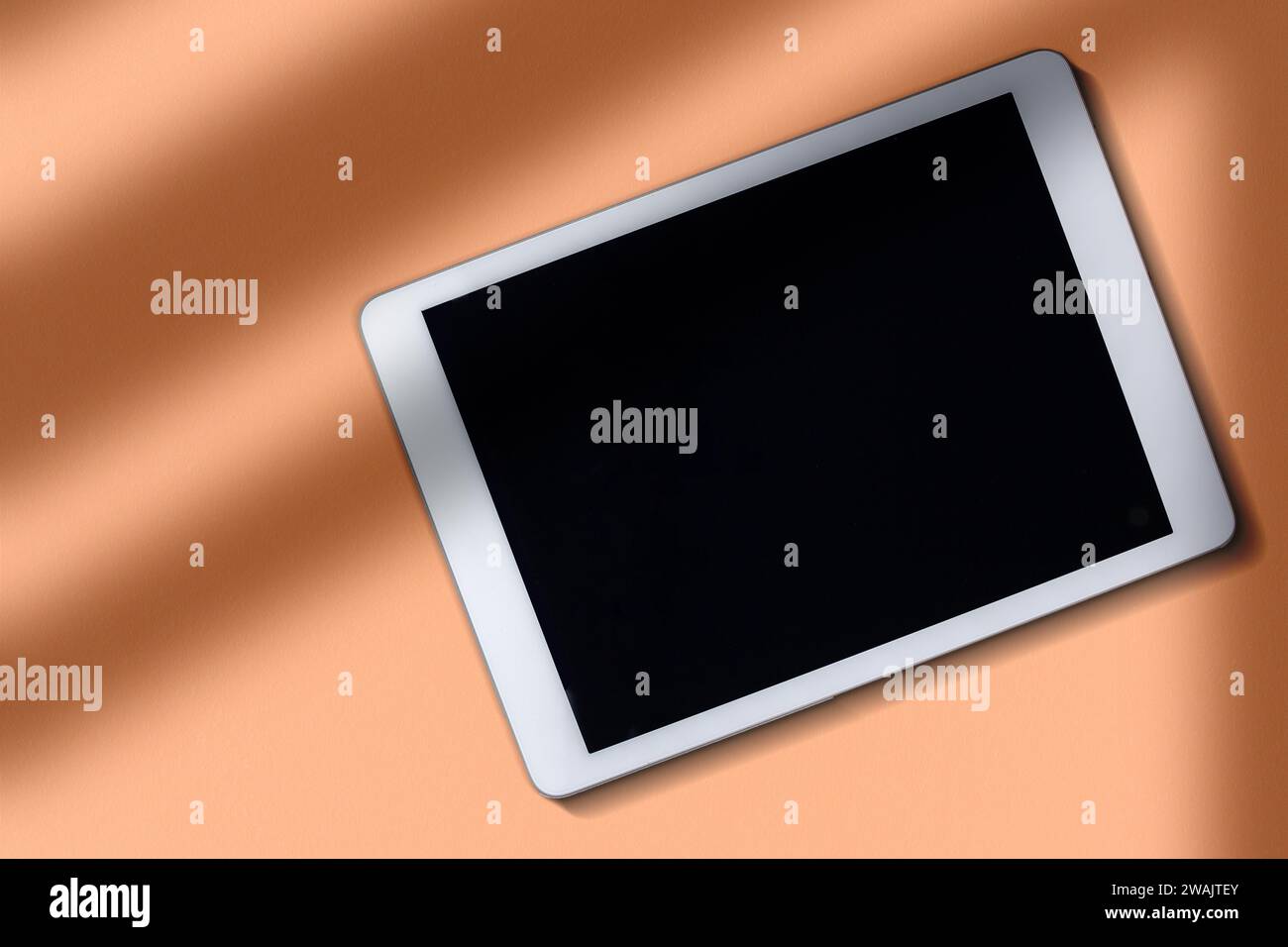Digital Tablet Mockup Bildschirm über Ebene Oberfläche in Peach Fuzz Farbe des Jahres. Kopfzeile mit Kopierbereich und leerem Bildschirm. Stockfoto