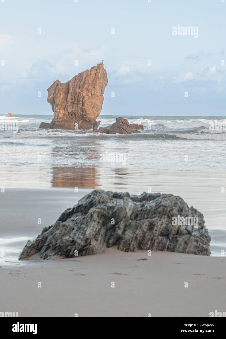 Ruhe an einem Wintermorgen in Playa del Aguilar in Asturien, Spanien. Ein Strand mit einem Naturdenkmal in der Mitte. Der Felsen von Playa del Aguila Stockfoto