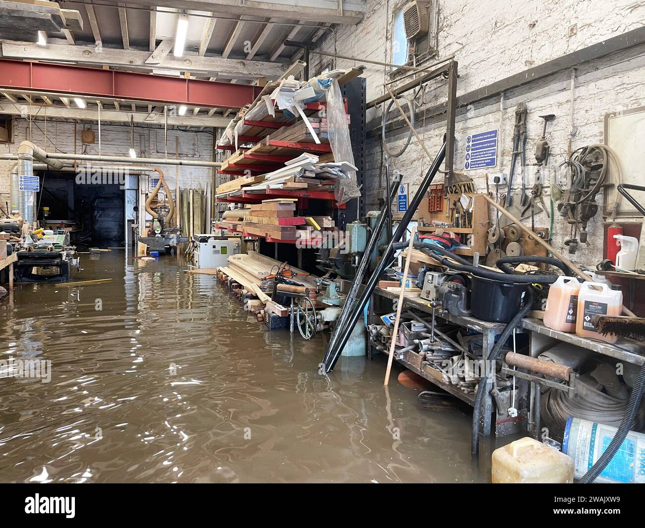 Hochwasser in Kirk and Bill's, einer Möbelwerkstatt in Newark-on-Trent, Nottinghamshire. Wasser ist durch die Dielen und Abflüsse aufgrund der Überschwemmung durch Sturm Henk gestiegen, die die Werkstatt überschwemmt hat. Bilddatum: Freitag, 5. Januar 2024. Stockfoto