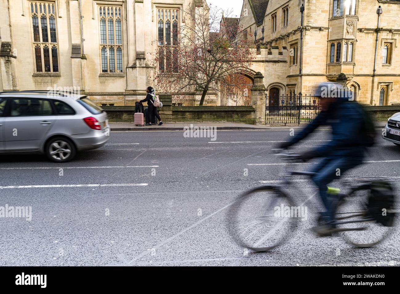 Zwei Autos, ein Fahrrad und ein Walker fahren auf dem Weg in die Stadt am Magdalen College Oxford vorbei Stockfoto