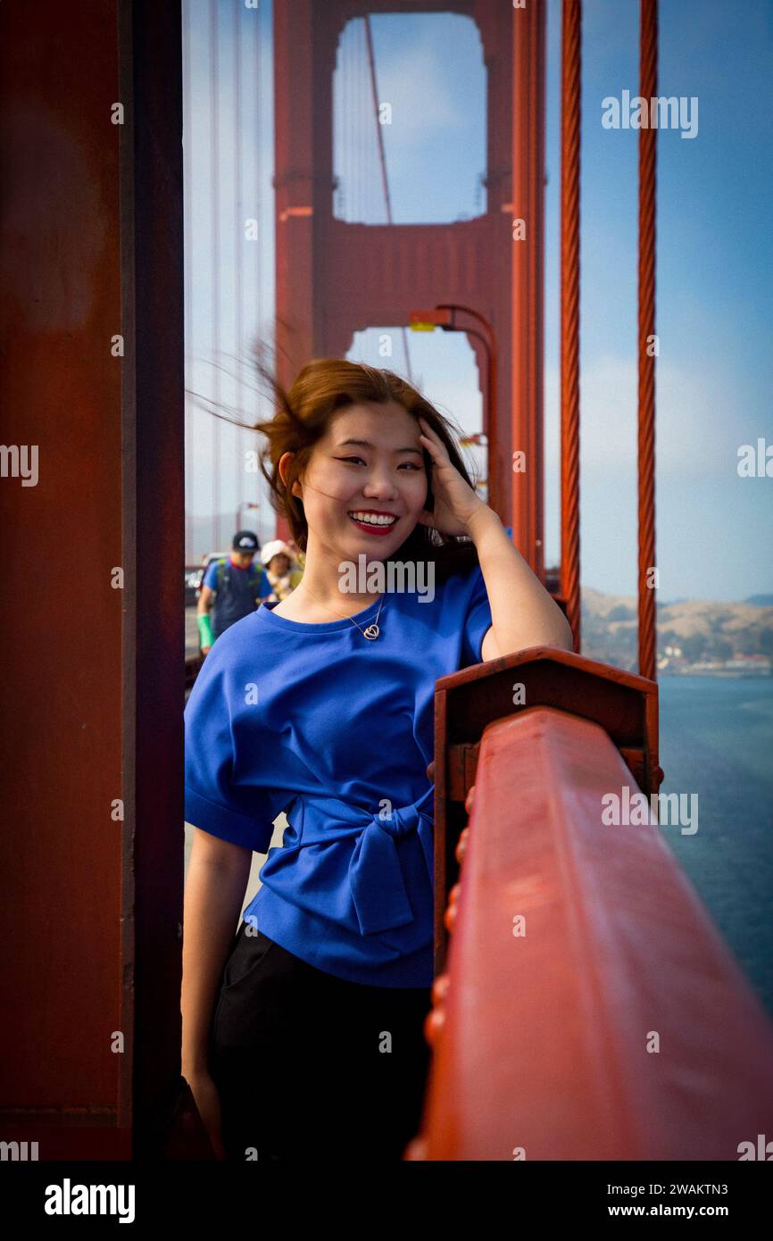 Chinesische Teen Tourist weibliche, vom Wind geblasene Haare, die auf dem Geländer an der Golden Gate Bridge stehen Stockfoto